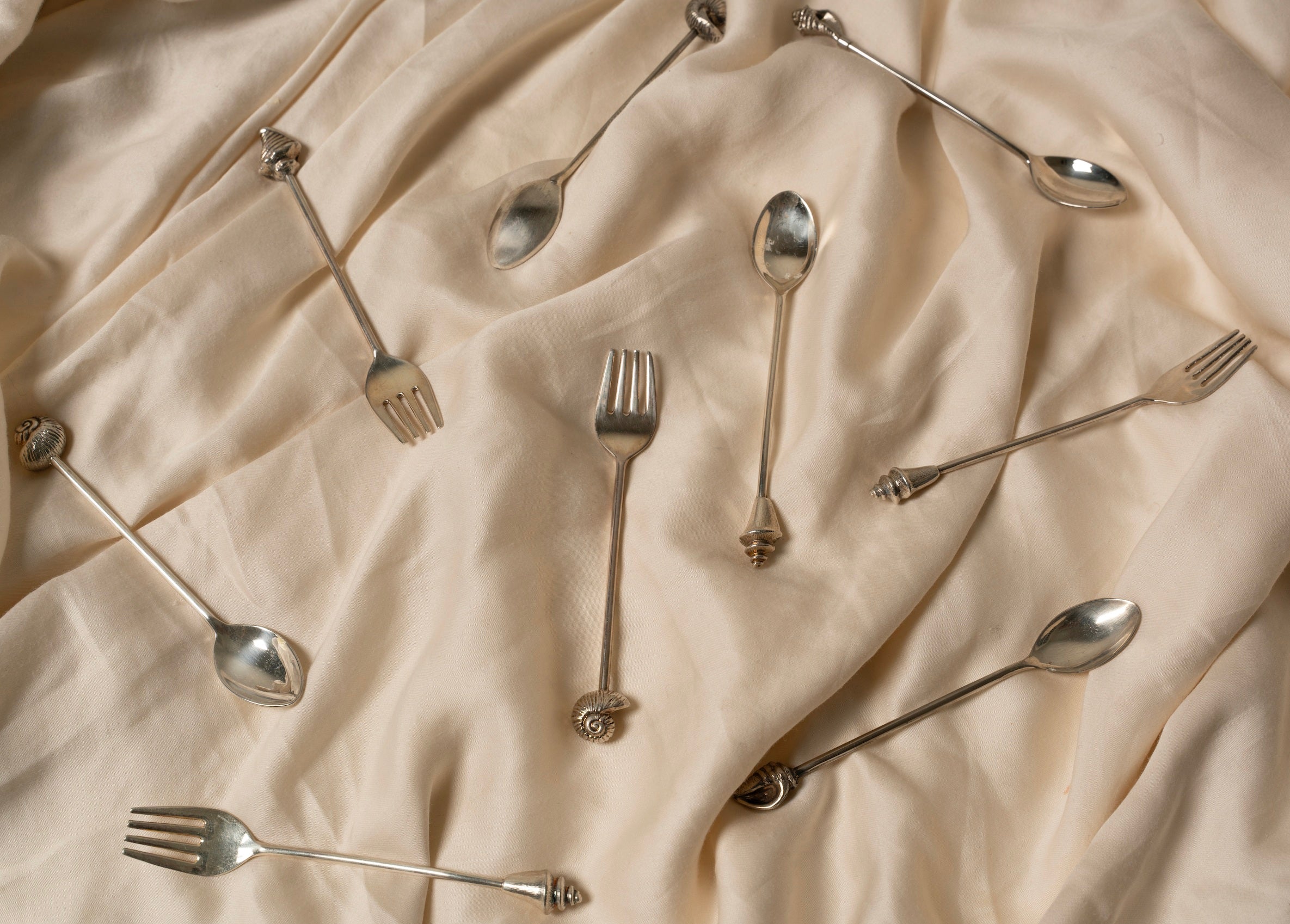 Silver Shell Fork Set of Two — arranged on soft beige fabric