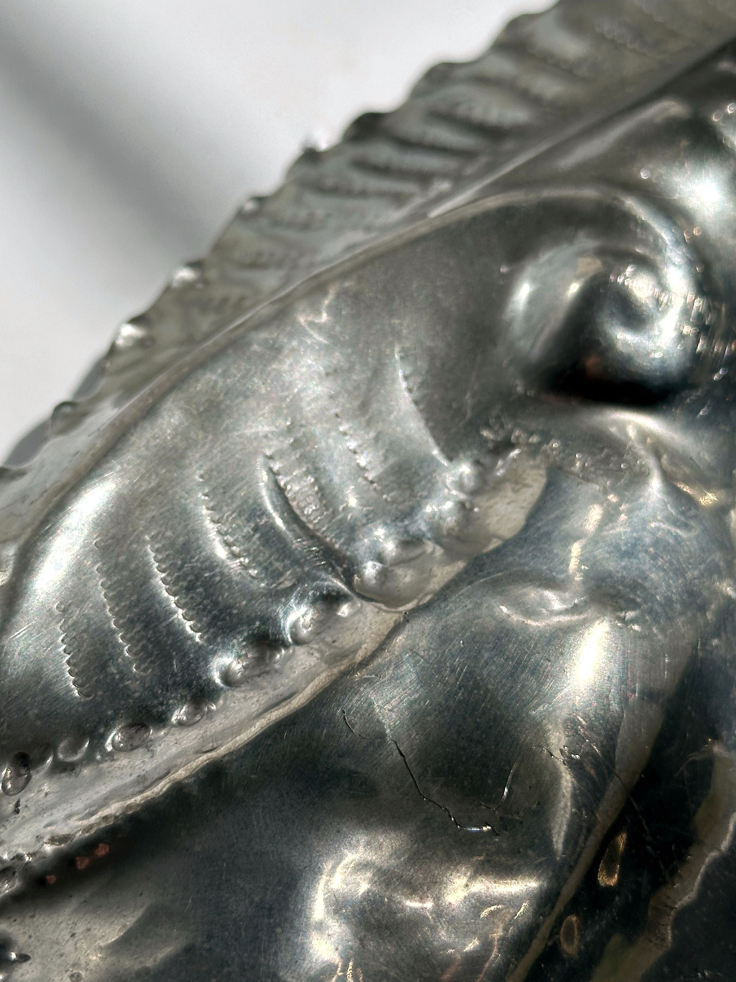 Close-up detail of handmade tin shell bowl showing metallic texture
