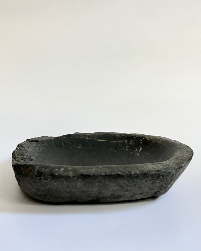 Antique black stone bowl with natural rough exterior texture