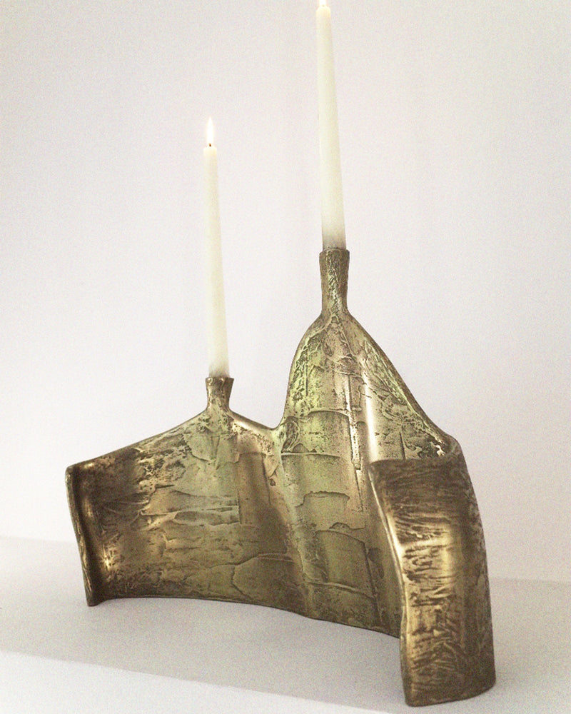 Bronze double candelabrum with textured finish and lit candles