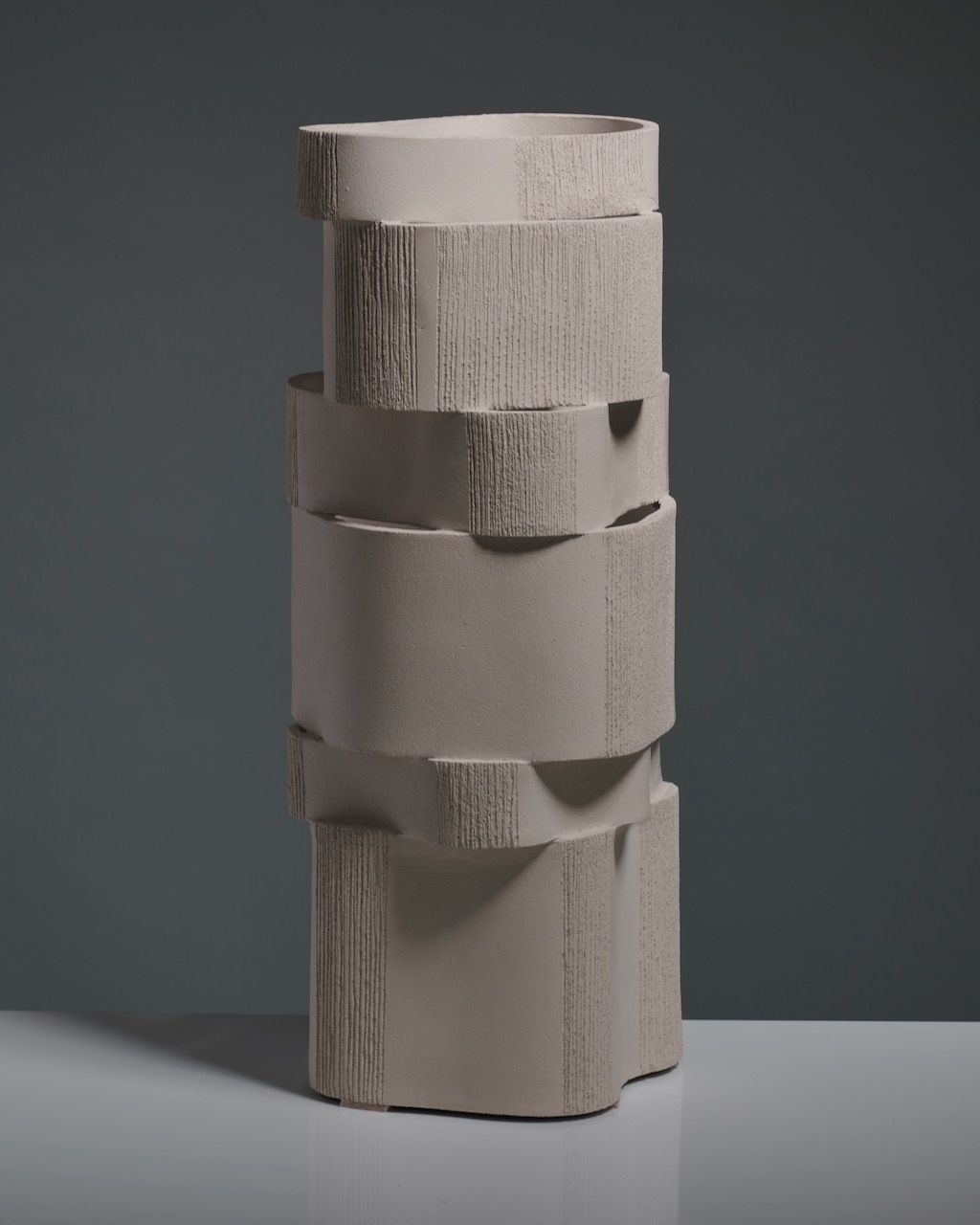 The 'Too 60' Ceramic Table Lamp by Katia Langeard is a tall, modern lamp with a matte light gray finish and alternating smooth and textured bands, giving it an irregular geometric stacked look.