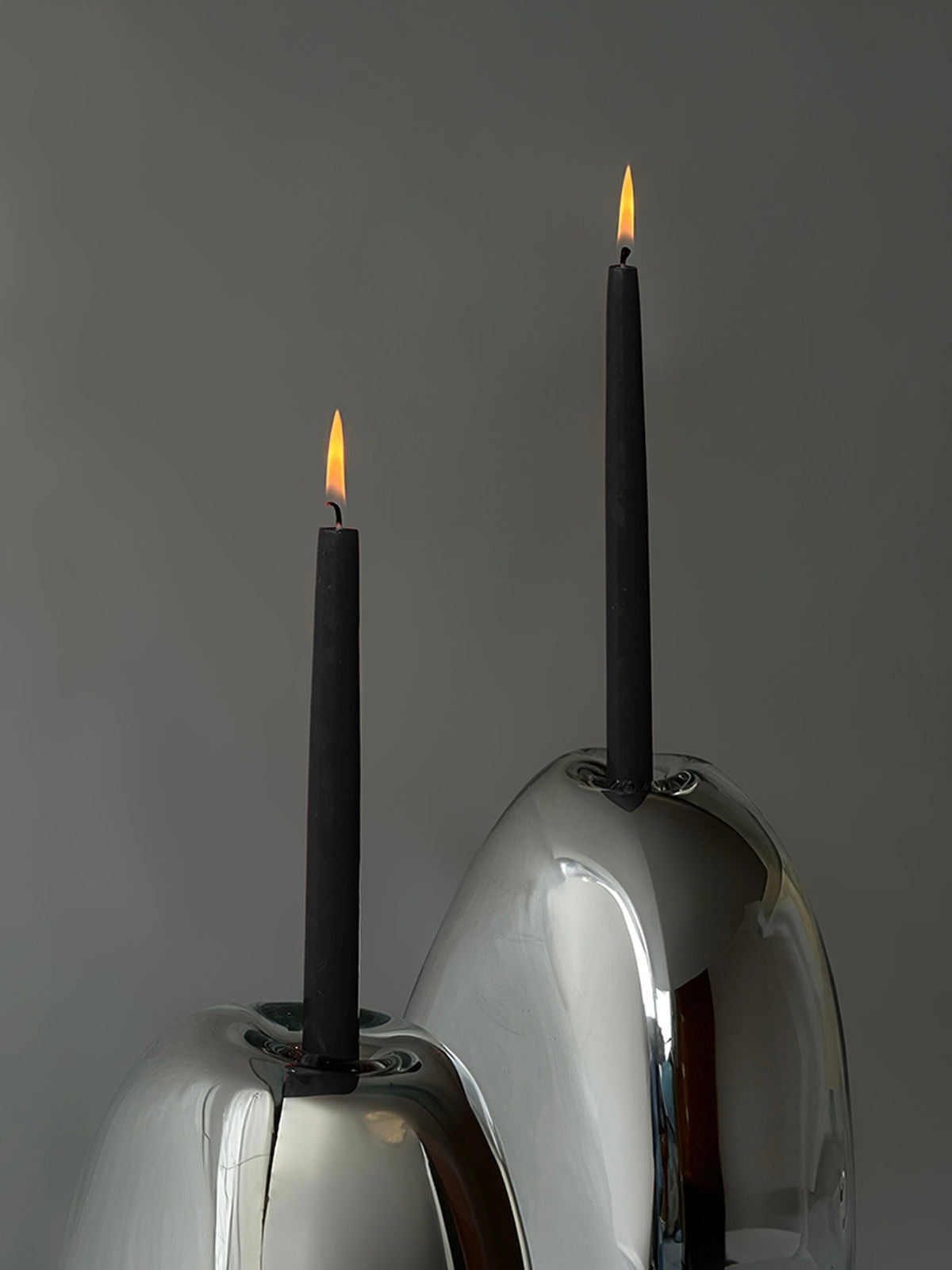 Lumos Candle Holders — close-up of polished silver surface with black candles