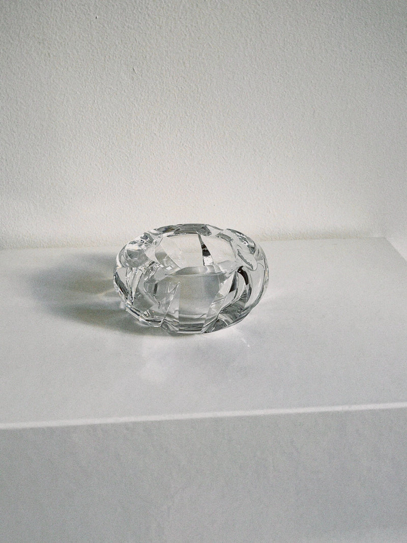 Clear crystal ashtray with faceted edges on white surface