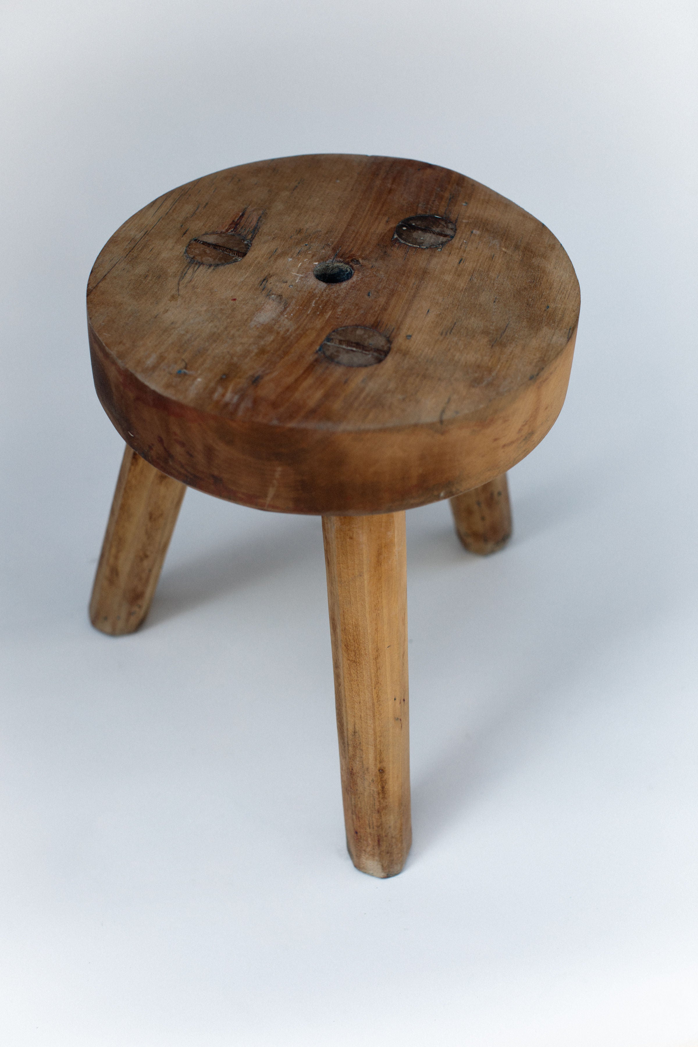 Rustic pine three-legged stool with weathered top detail