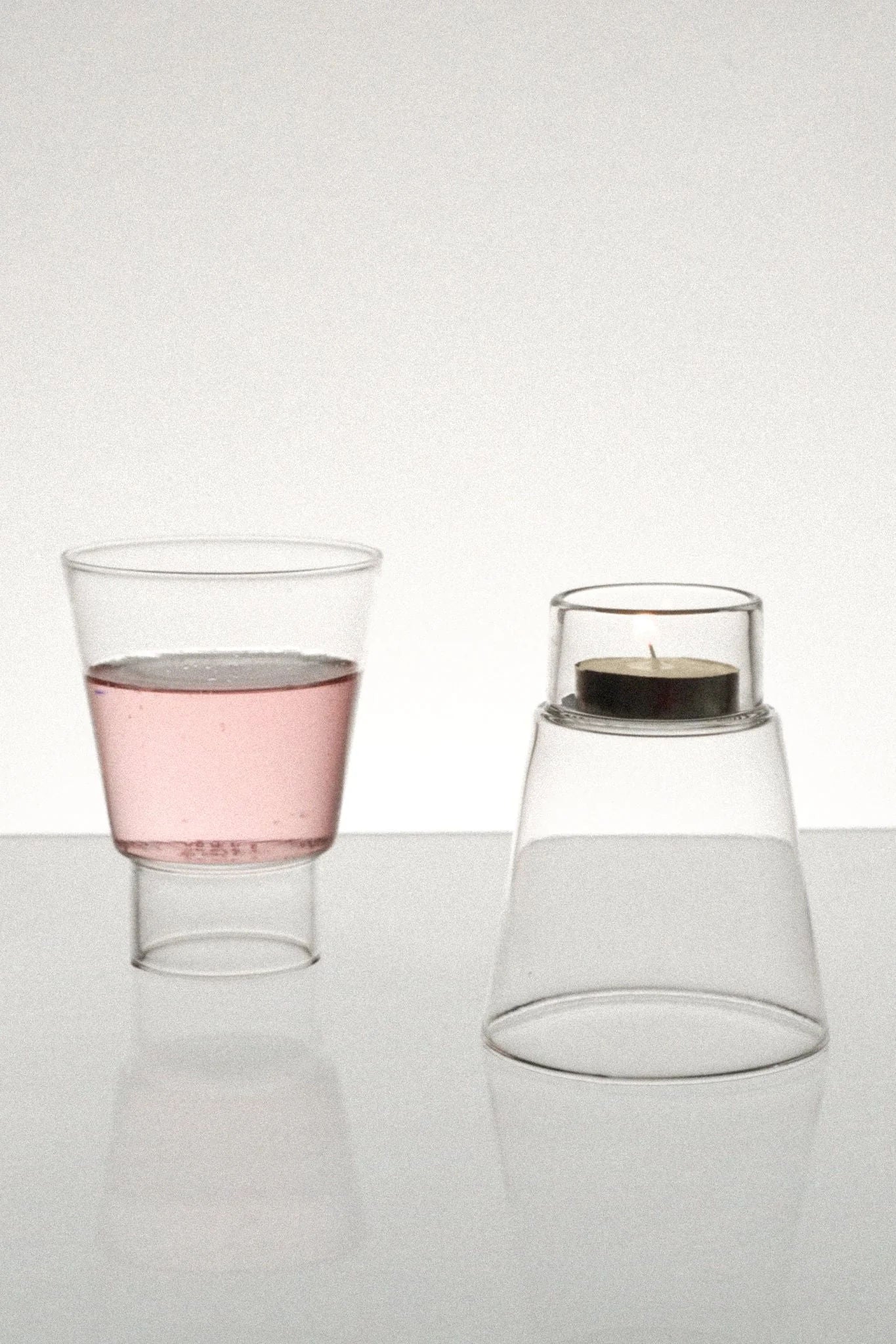 Podio' Glass - Clear — angled view with pink liquid and candle