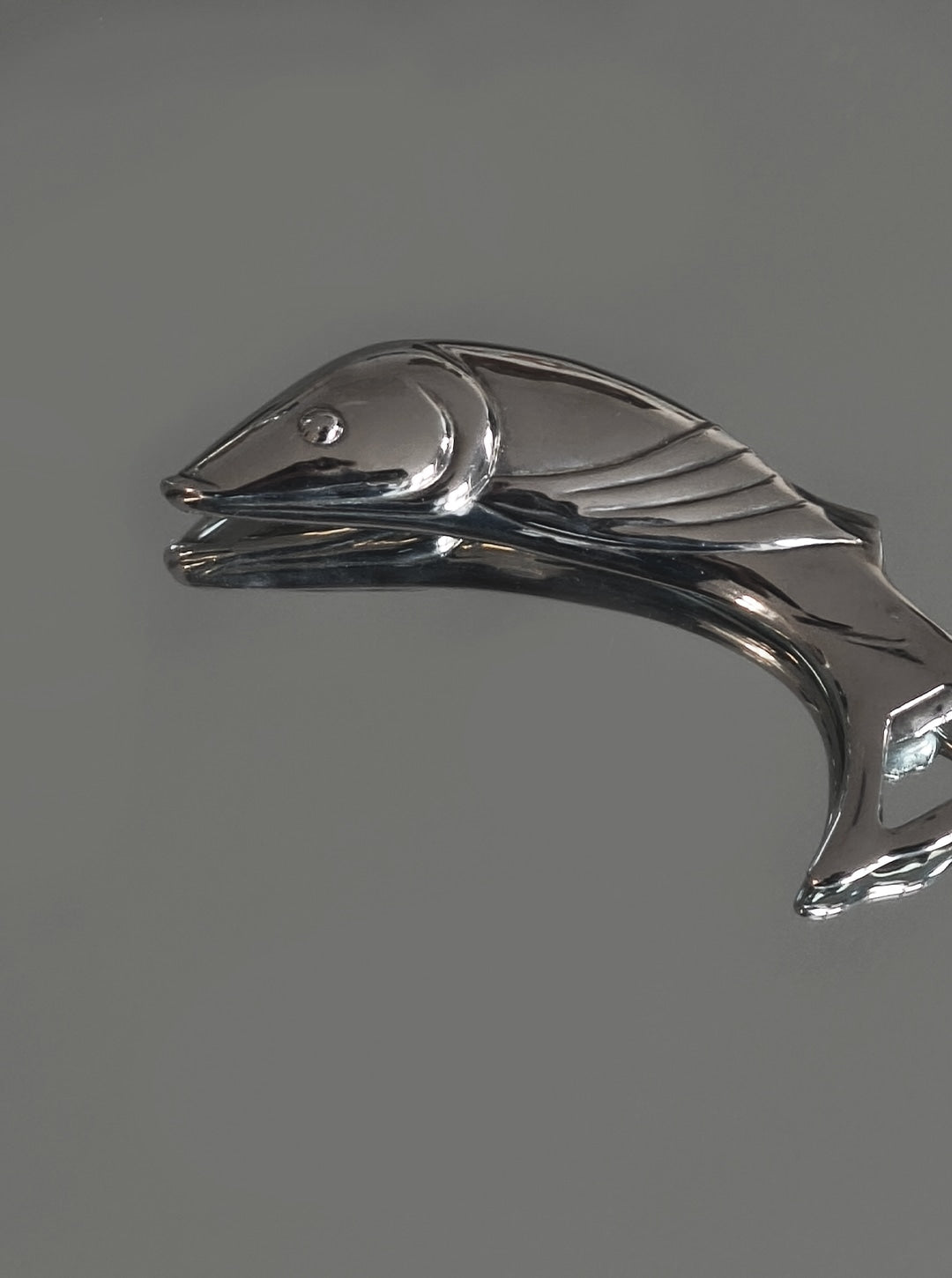Art Deco Fish Bottle Opener — side view on reflective surface