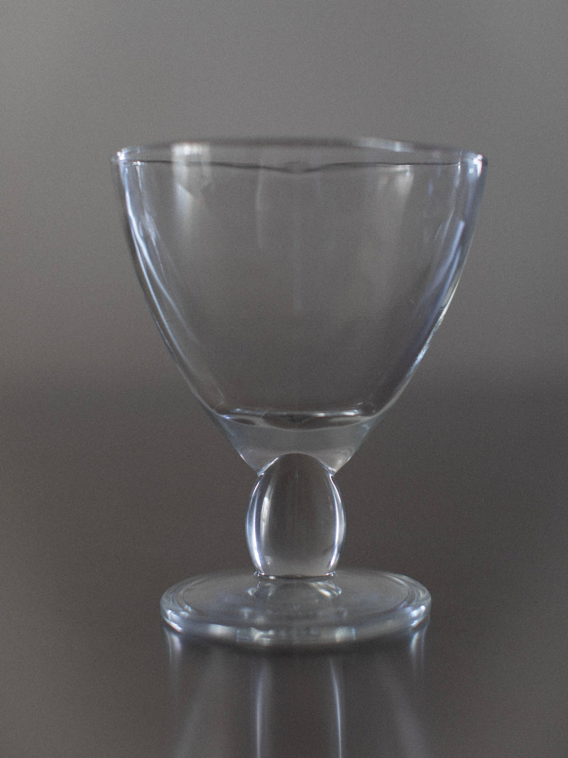 An elegant Out For Lunch Italian Dessert Cup, featuring a wide bowl and round base, sits on a reflective surface against a neutral gray background—a perfect example of stylish pre-loved glassware.