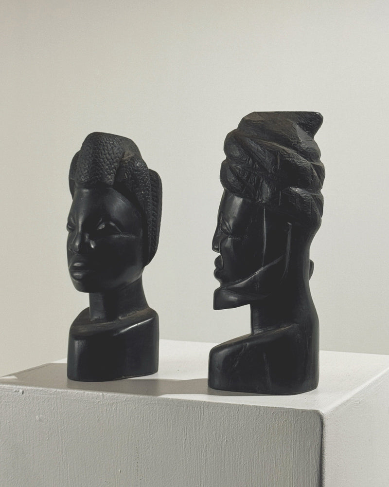 Two carved ebony African busts side by side on white display