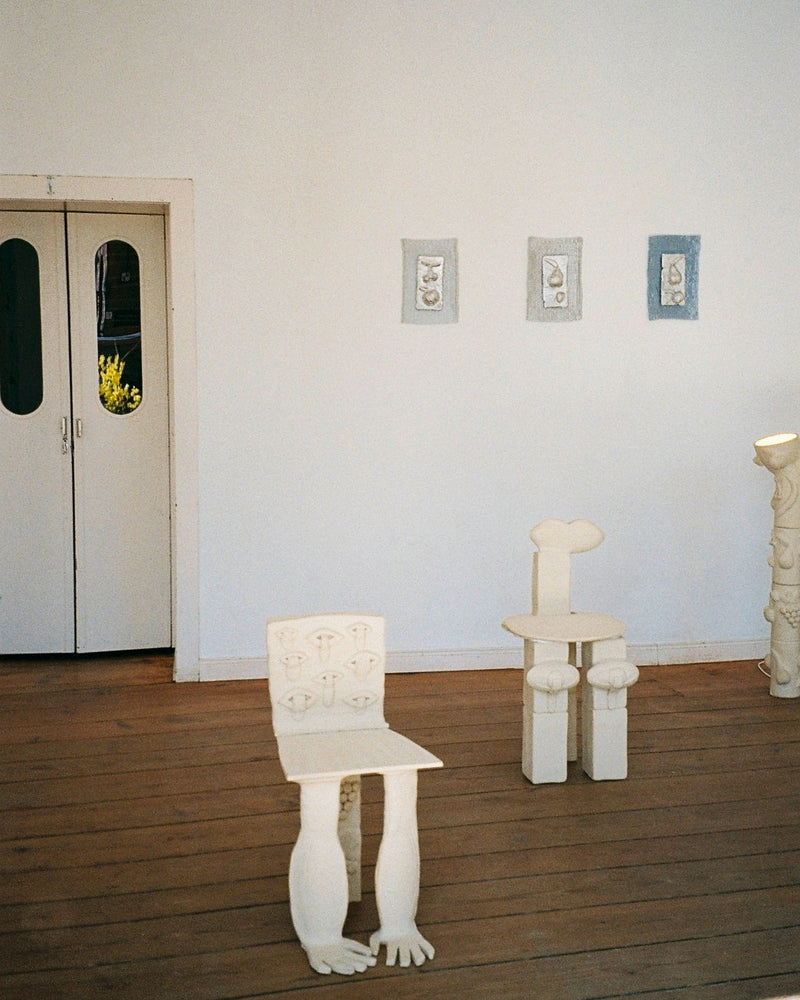 Contemporary white sculptural chairs and wall art in gallery setting