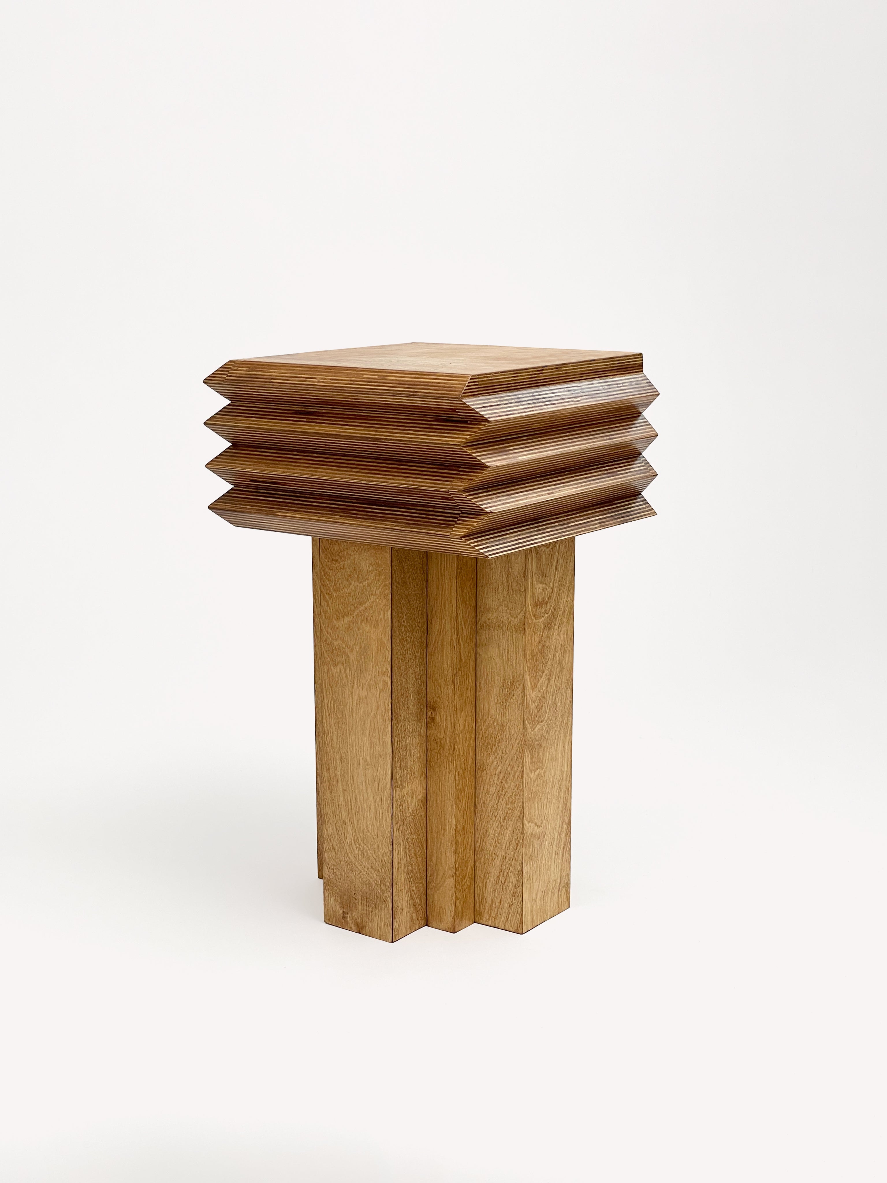 The MM Stool - Butterscotch by GOONS features a modern square-top wooden design with a layered, zigzag-edged midsection—ideal for fans of customizable furniture and inspired by Goons' iconic style, shown here against a plain white background.