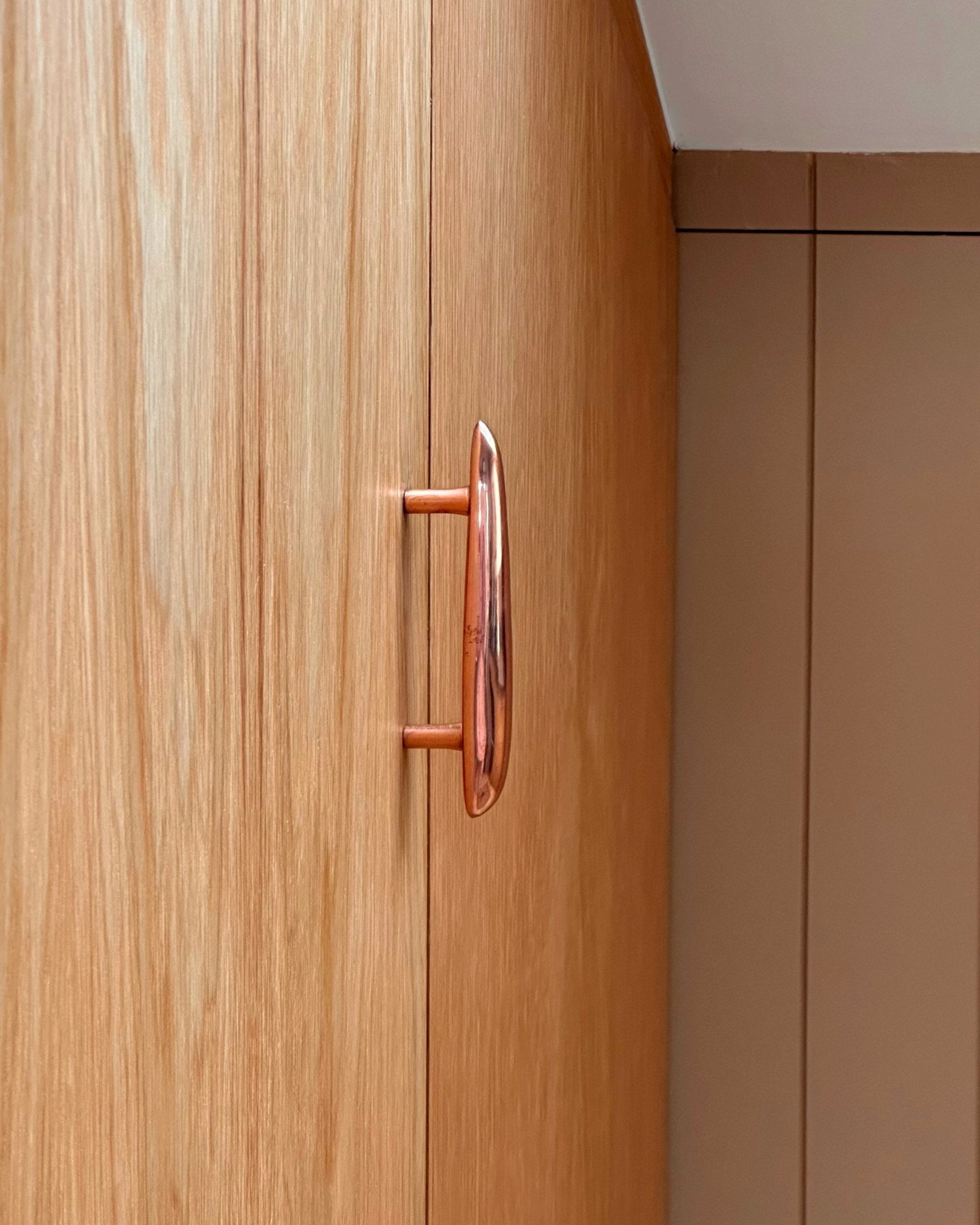 MOMI Cabinet Pull — close-up of copper handle on wooden cabinet