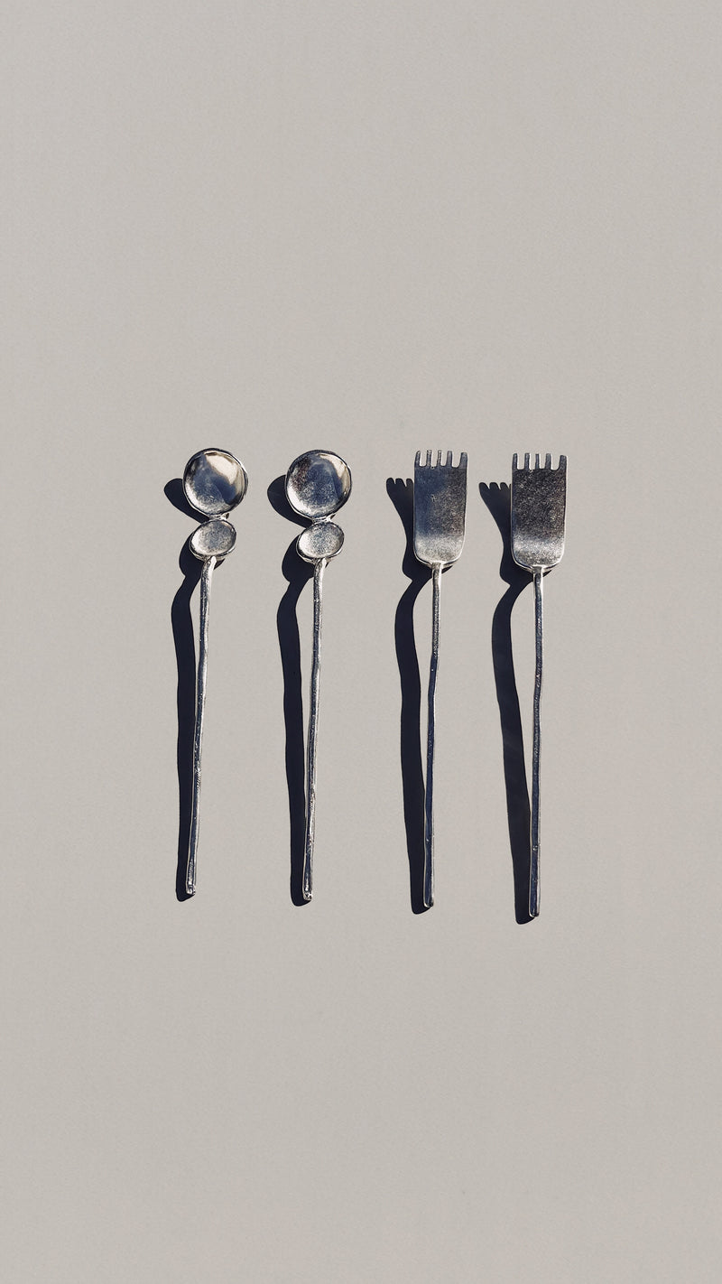 Four silver artifact tea spoons with round bowl heads and fork tines