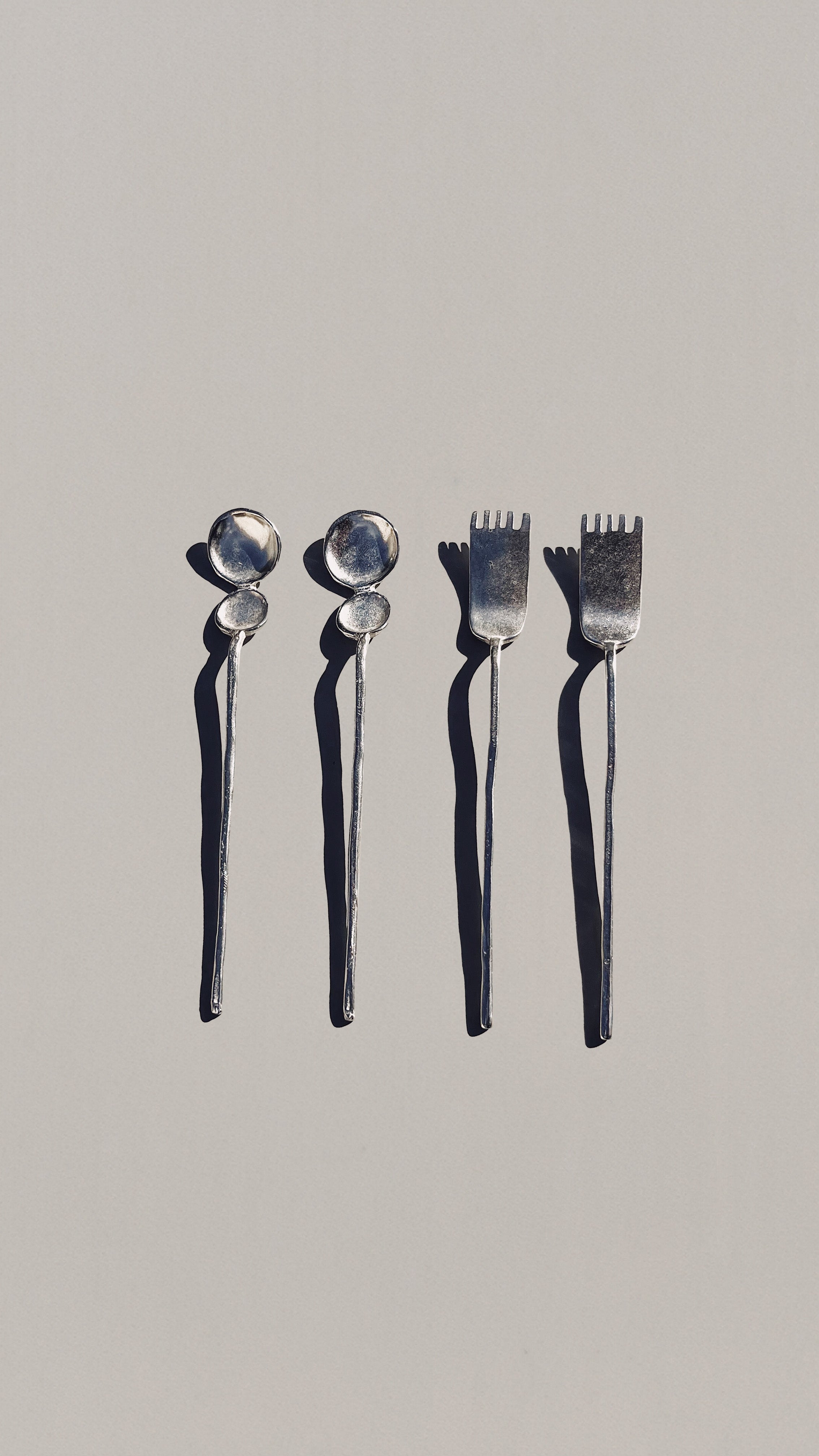 Four silver artifact tea spoons with round bowl heads and fork tines