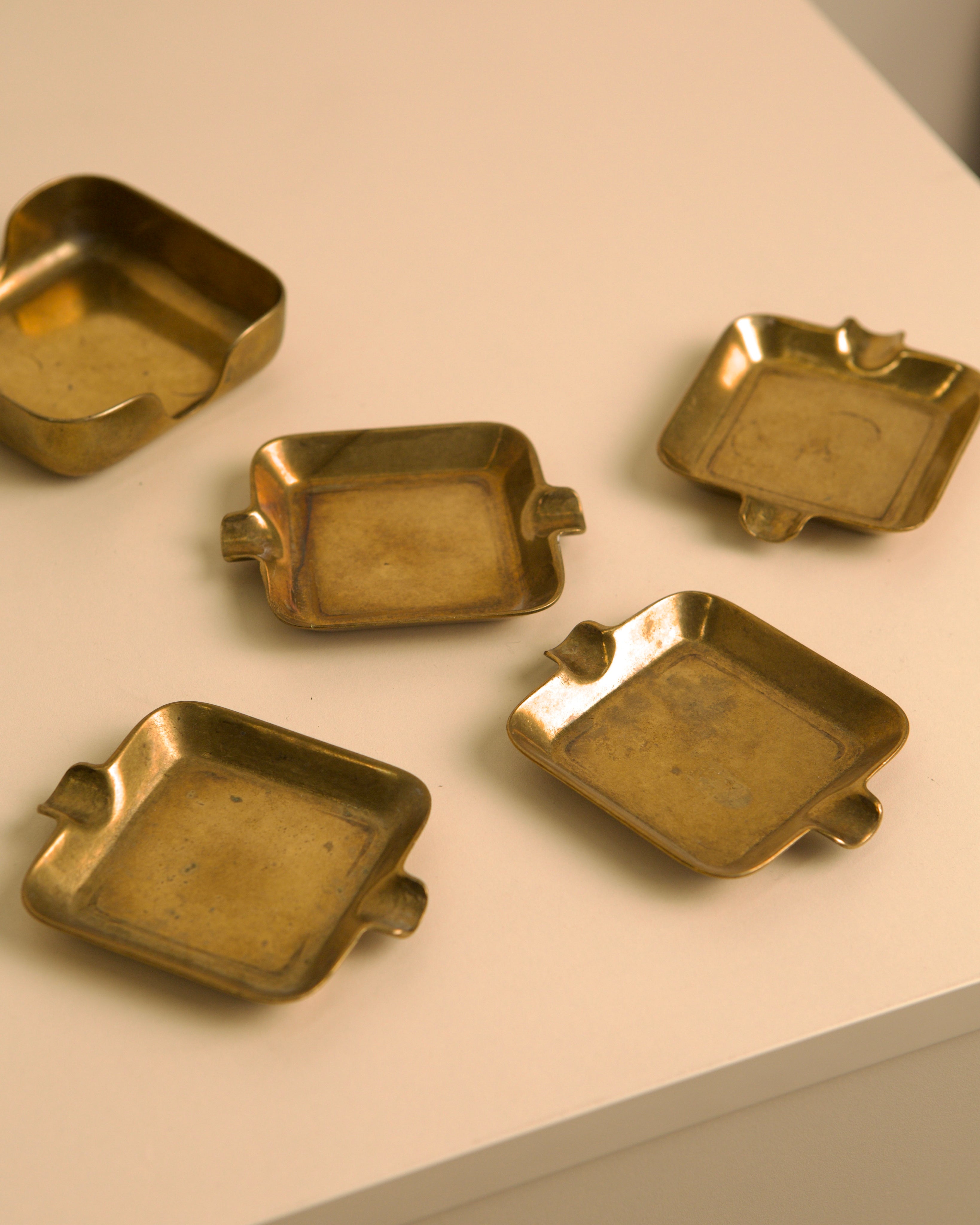 Set of five Italian brass ashtrays from 1960s on white surface