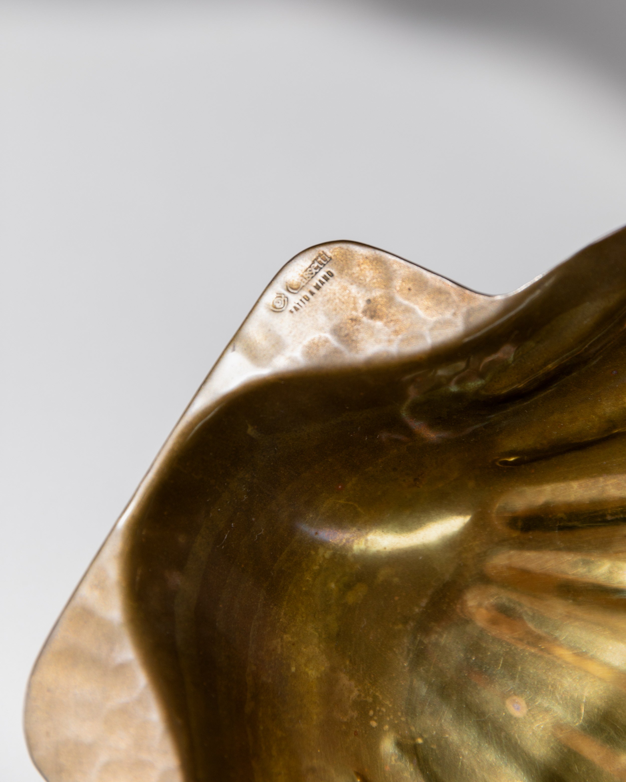 Close-up detail of brass bowl showing maker's mark and patina