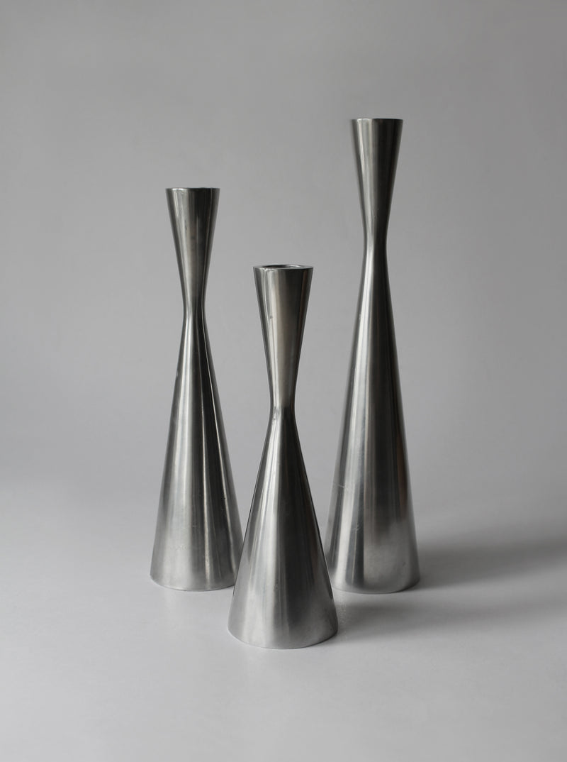 Three polished aluminum candle holders in varying heights