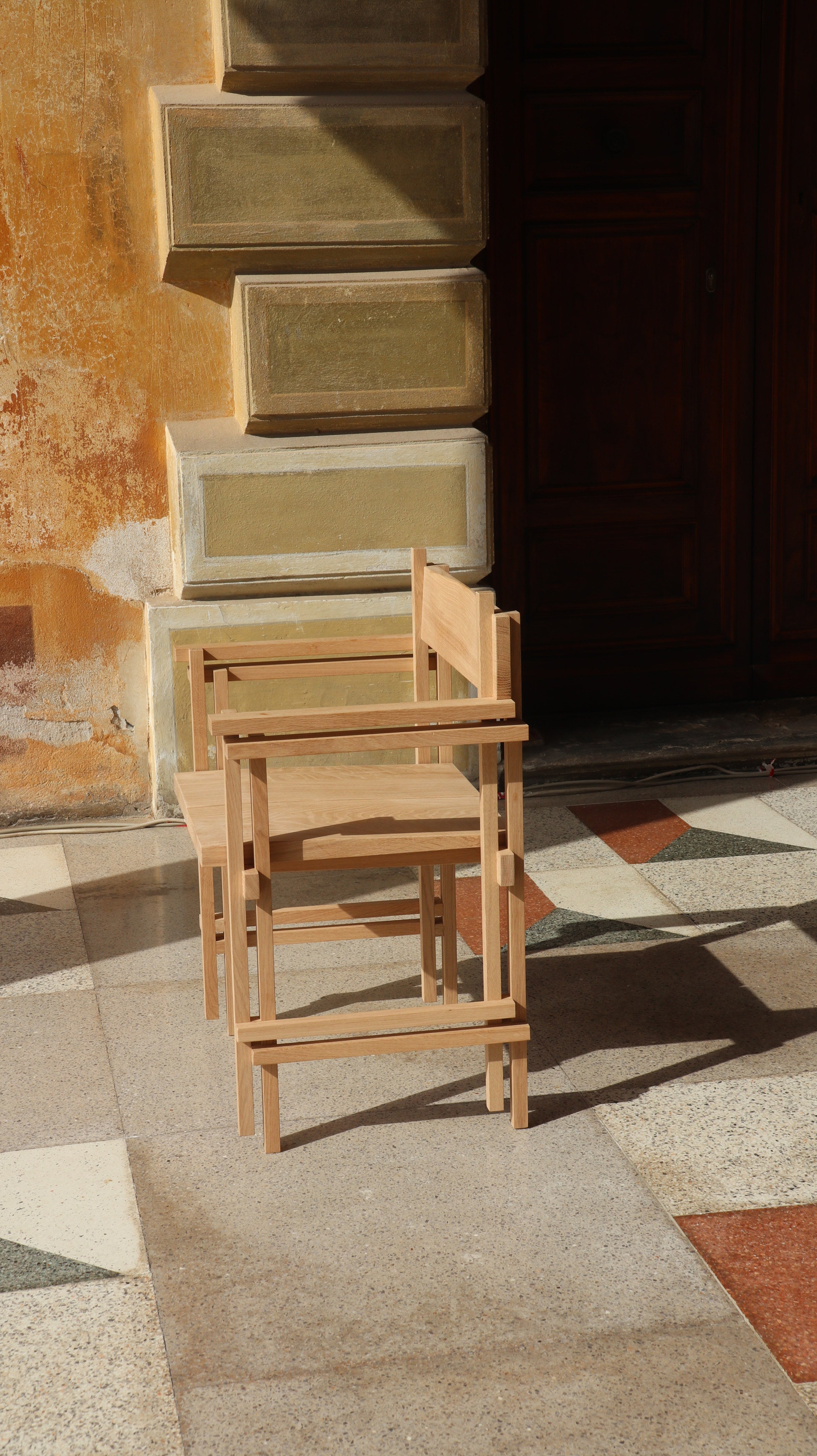 Stack chair with armrests — side angle on patterned floor