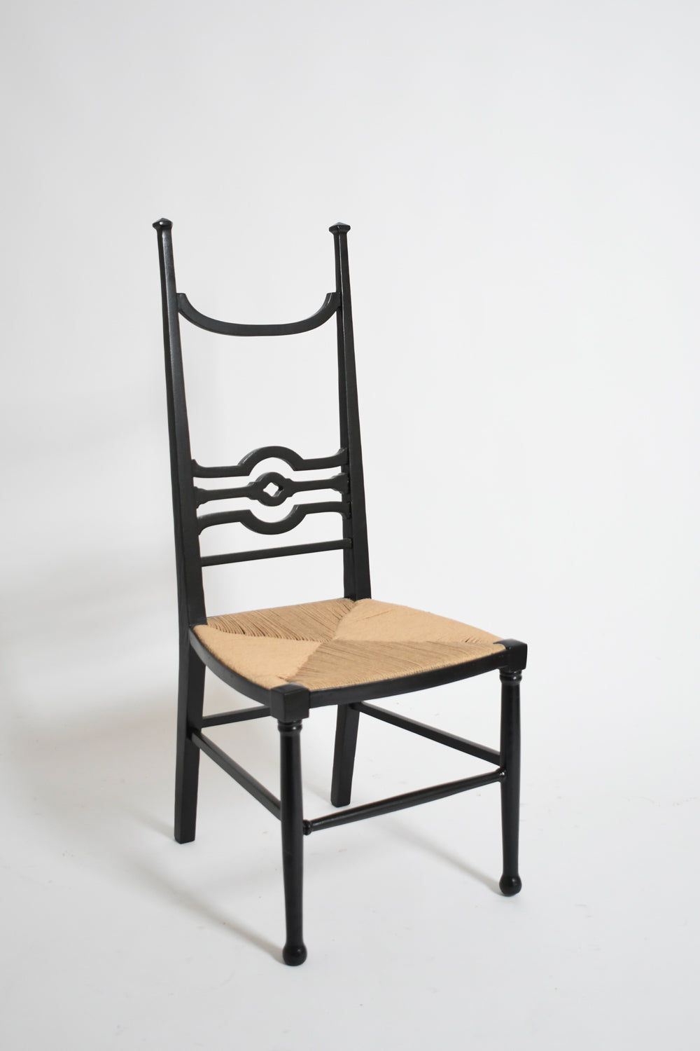 The Arts & Crafts Ebonised Wood Chair, 1900s by Barracuda Interiors features a tall backrest with circular patterns and a woven natural seat, shown against a plain white background.