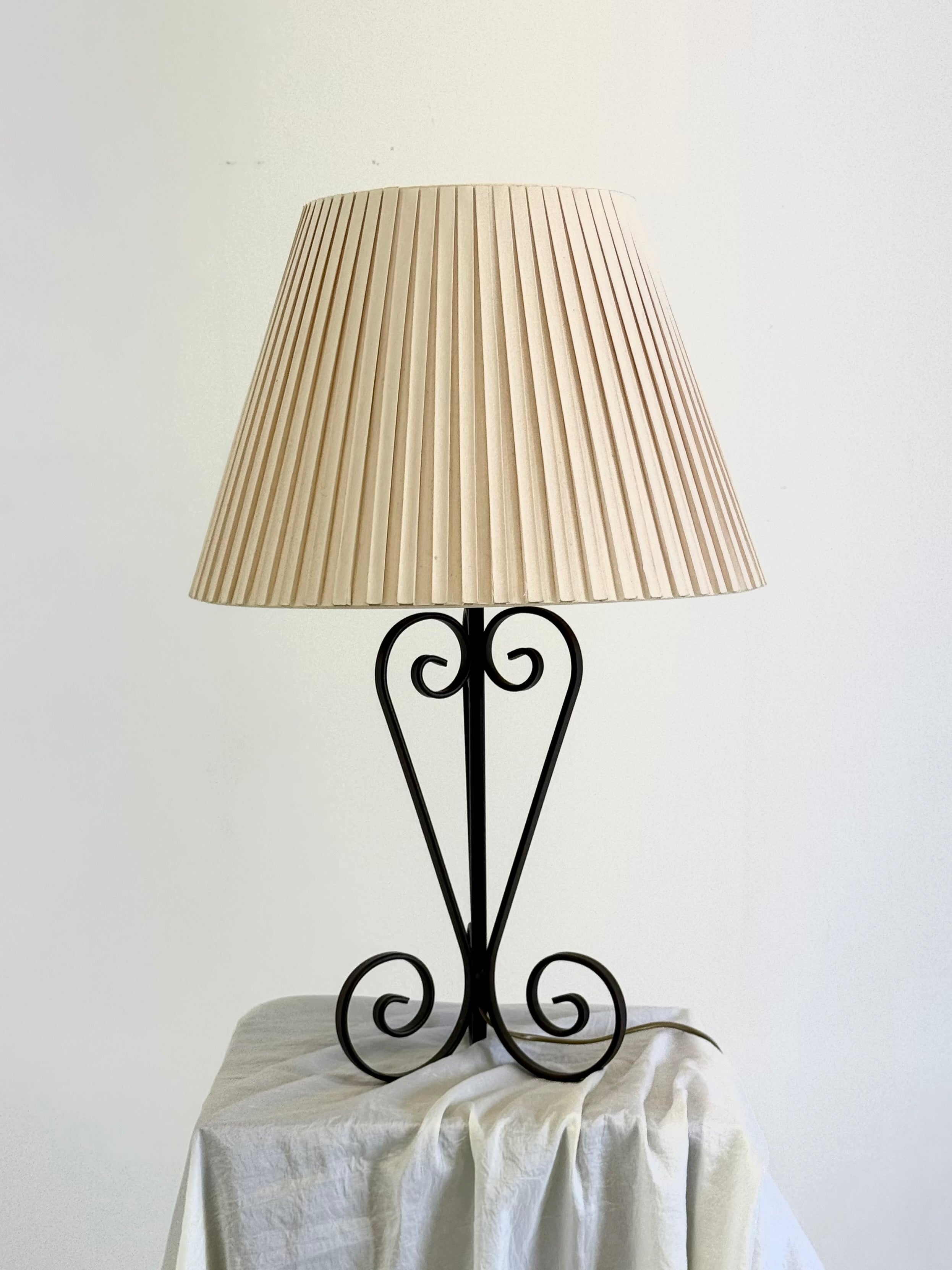 Vintage wrought iron table lamp in a swirl shape with a pleated shade — close-up