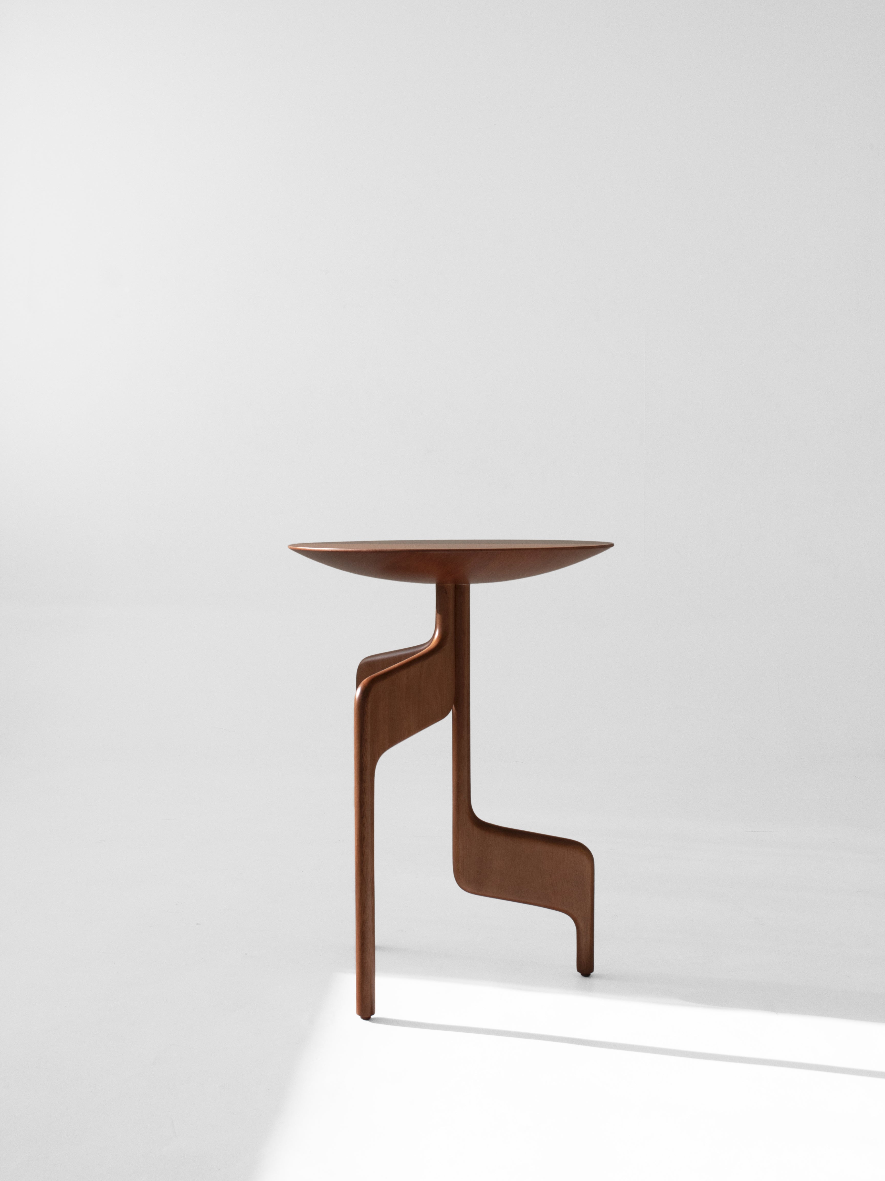 The "Vereda" Side Table by Luciano Costa Estúdio features a modern round top and uniquely curved, asymmetrical solid jequitibá legs from the Nômade collection, shown against a plain white background.