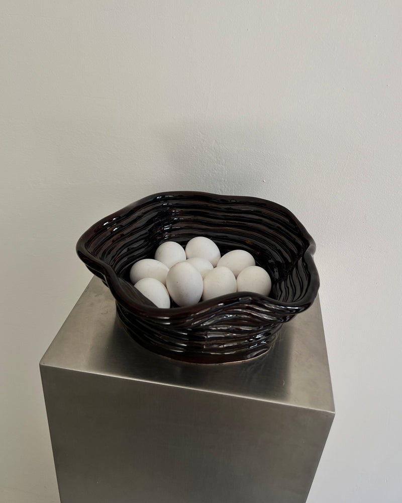 Chocolate gloss ceramic bowl with white eggs on pedestal display
