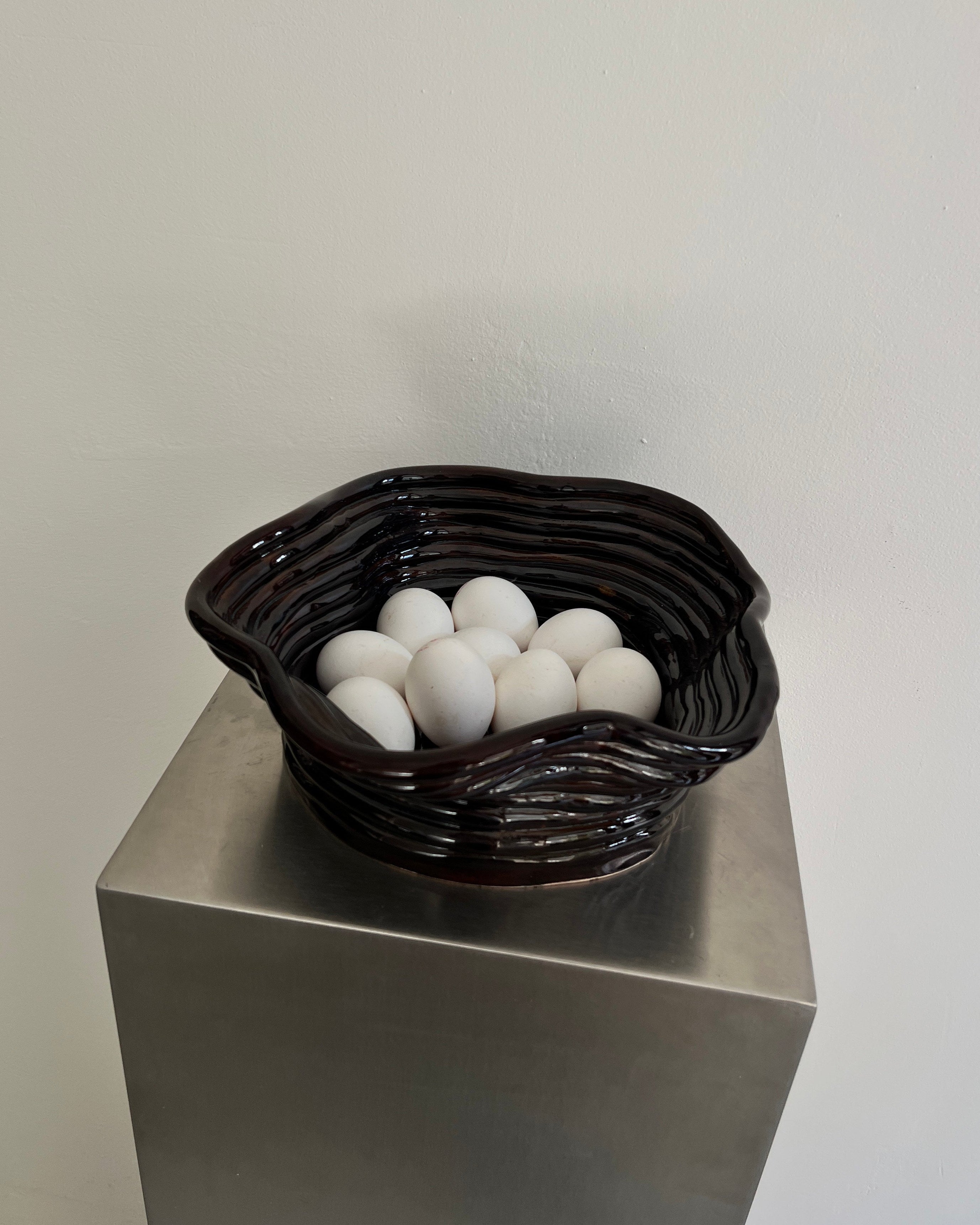 Chocolate gloss ceramic bowl with white eggs on pedestal display