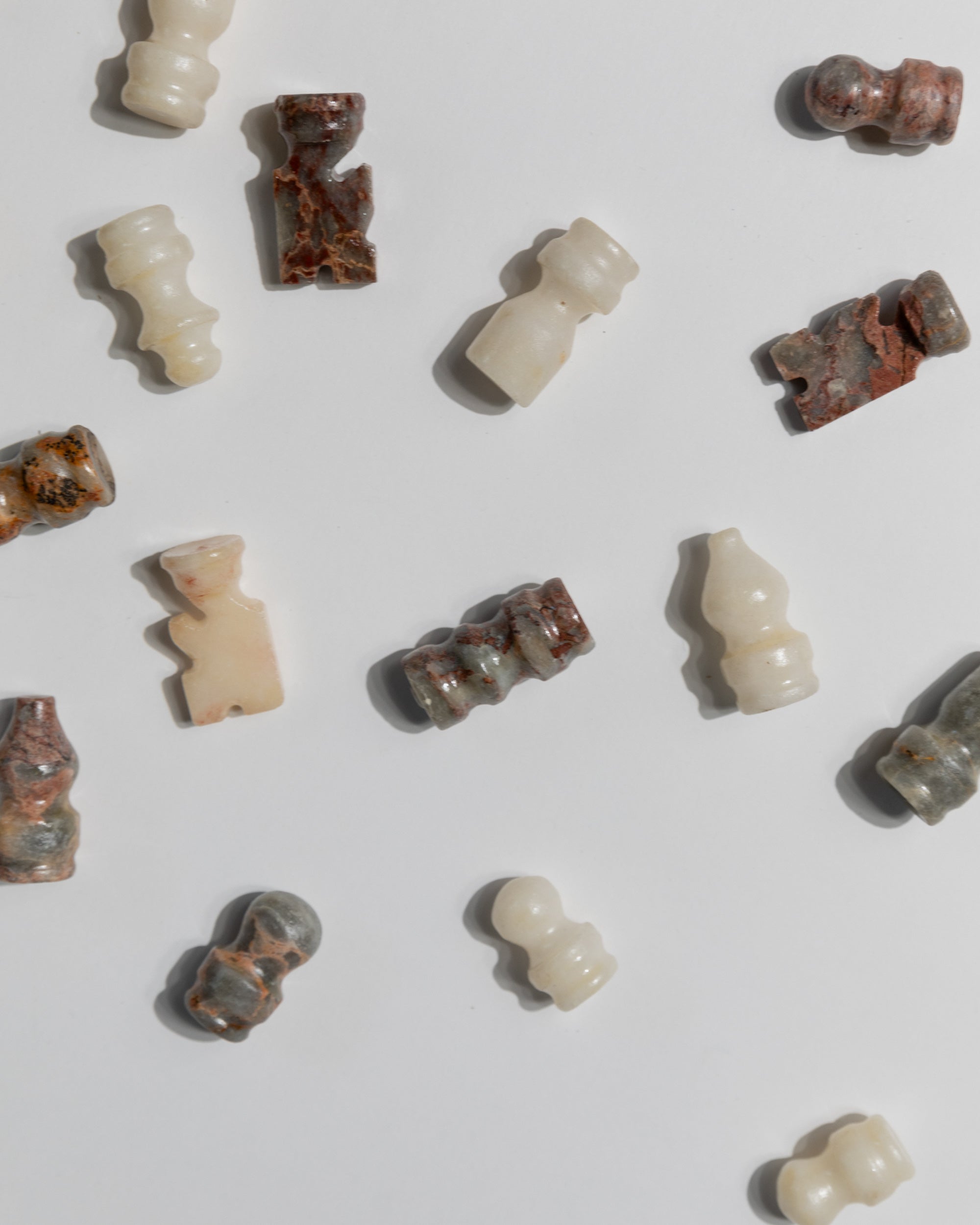Individual vintage marble chess pieces in white and rosé tones