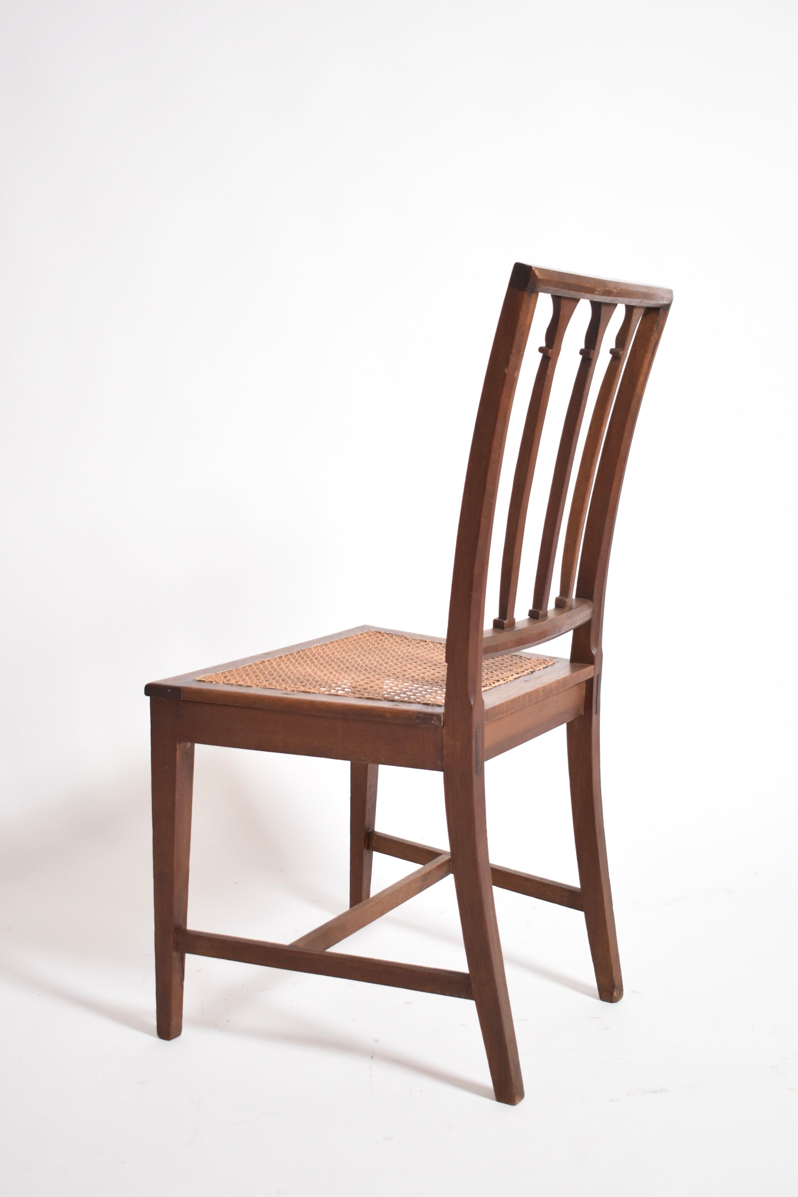 A pair of Dona Maria Chairs by Barracuda Interiors, 19th c—crafted in wood with woven cane seats and slatted backrests—elegantly displayed angled against a plain white background, evoking antique charm.