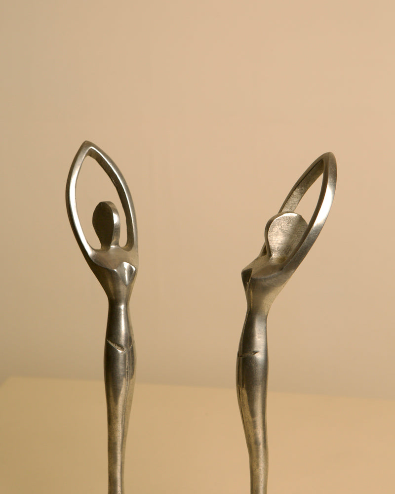 Pair of Italian aluminum dancers from the 80s — close-up of figures with raised arms
