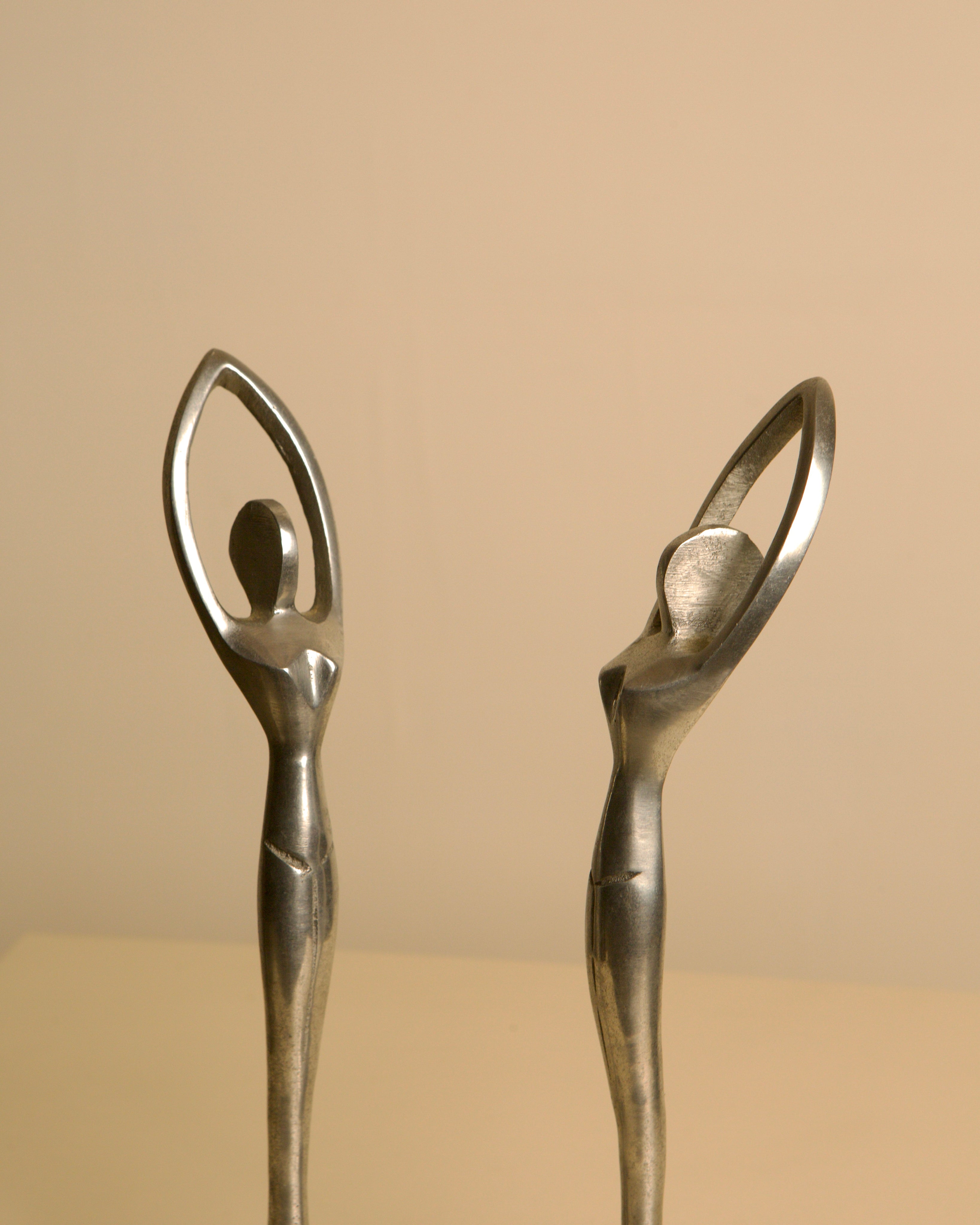 Pair of Italian aluminum dancers from the 80s — close-up of figures with raised arms