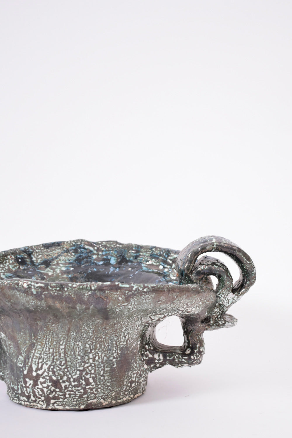 The Helder Handles Large Ceramic Bowl, 2025 by Barracuda Interiors features a textured metallic finish, rough uneven rim, and uniquely twisted handles, presented against a plain white background.