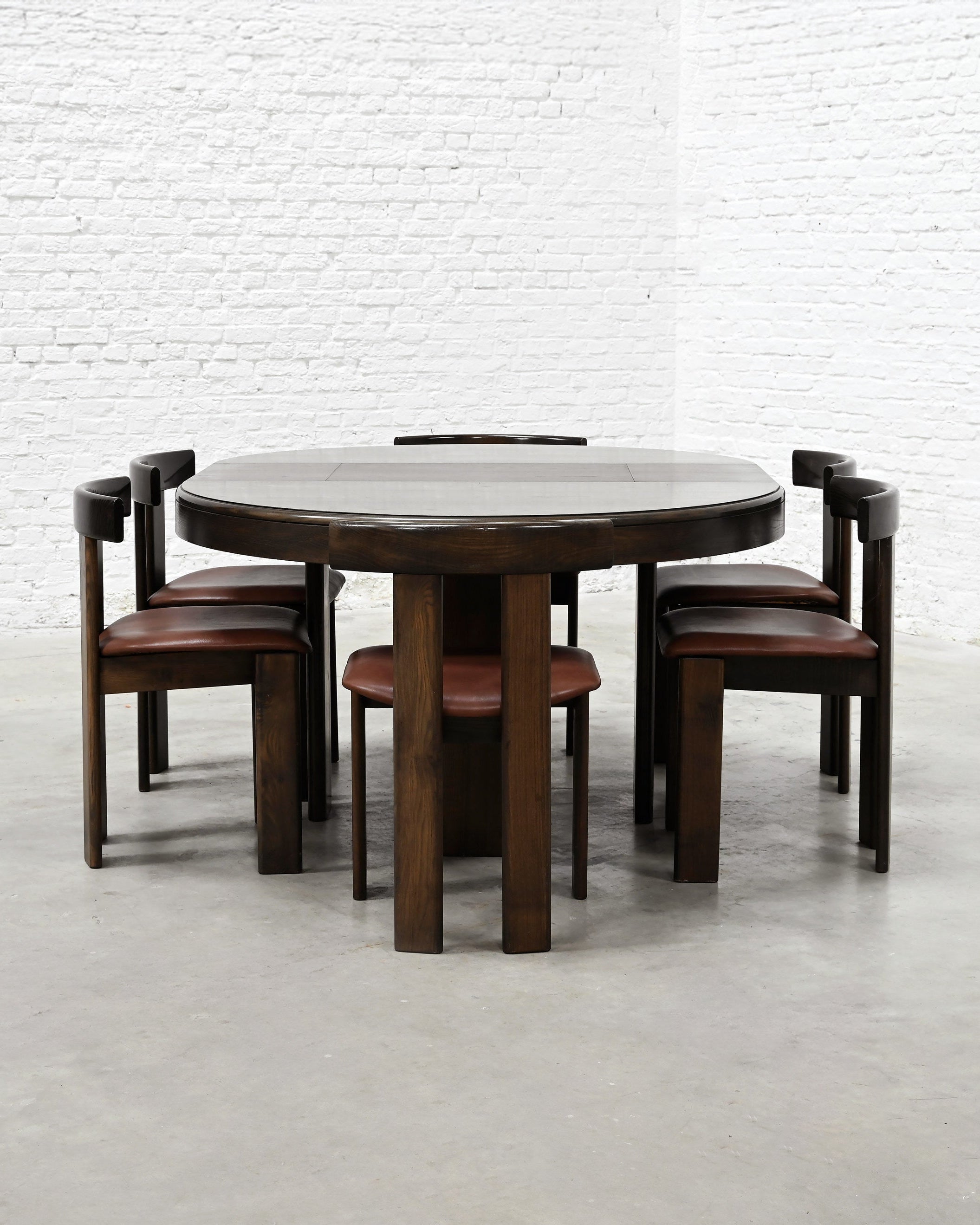 Round walnut dining table with six leather chairs by Luigi Vaghi