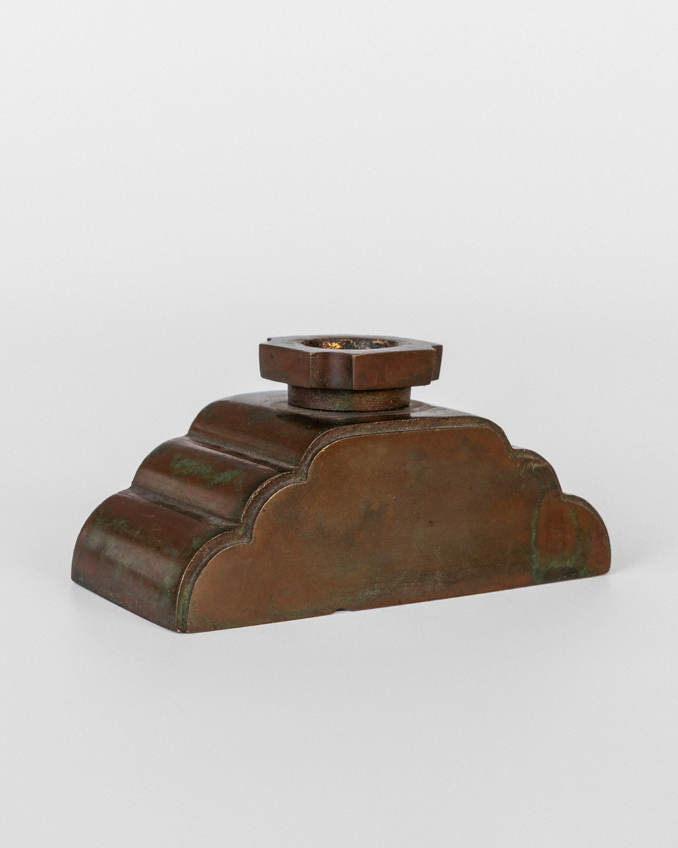 Bronze candleholder base detail showing patinated stepped form