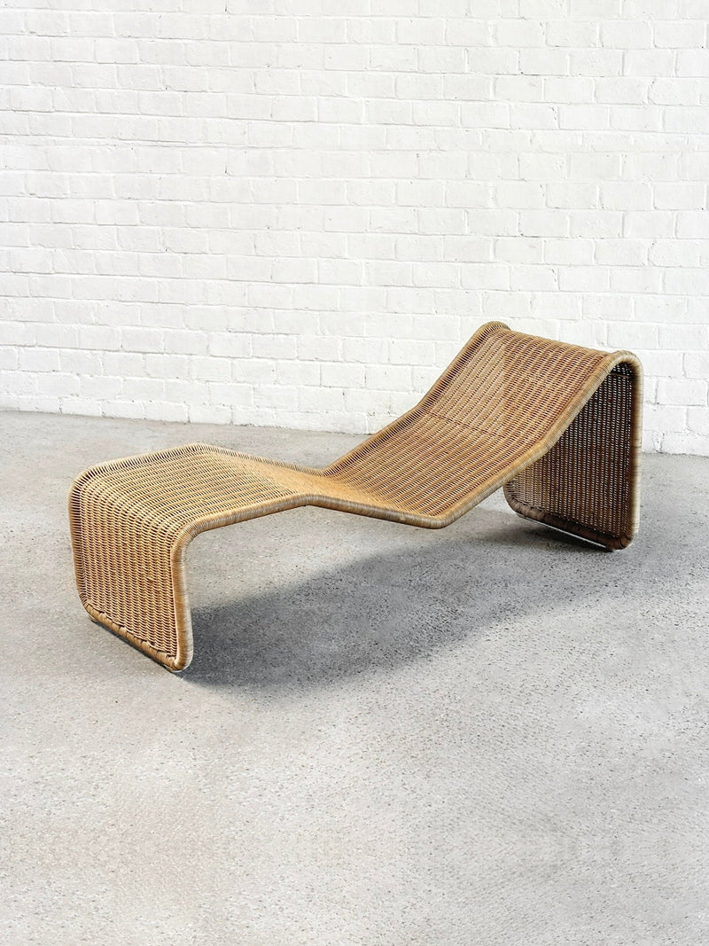 The P3 Lounge Chair by Tito Agnoli (Italy, 1960s) for Introverso features smooth curves and an airy, wave-shaped rattan design, shown here on a concrete floor against a white brick wall.