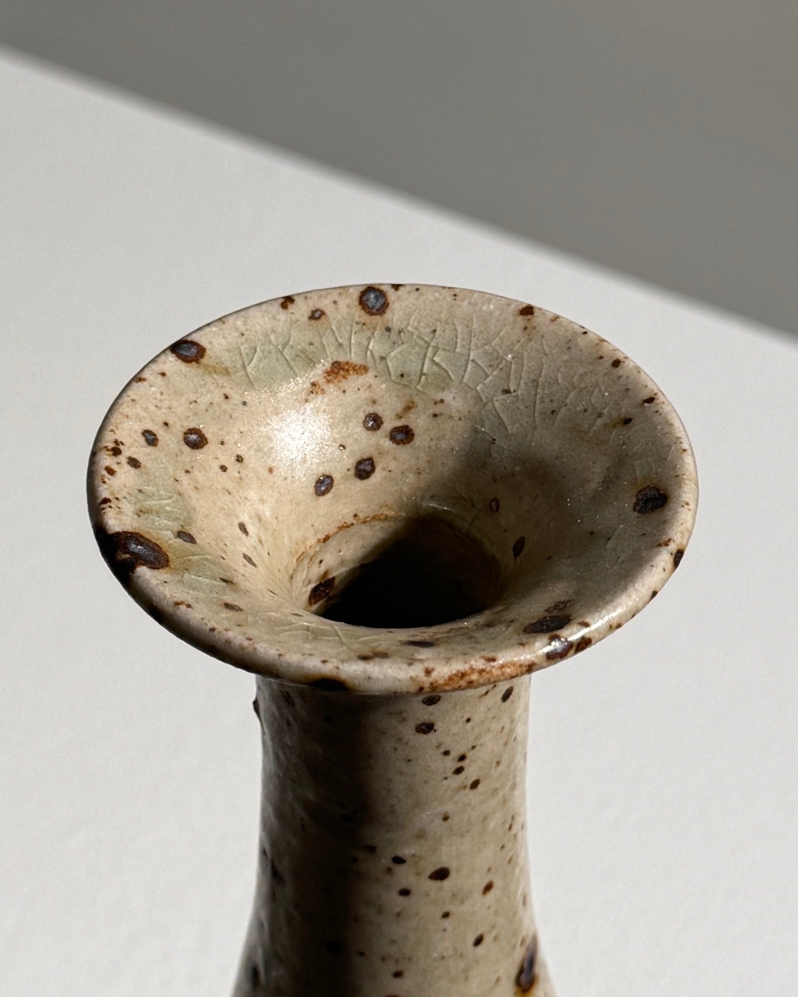 Close-up view of speckled stoneware vase rim with etched details