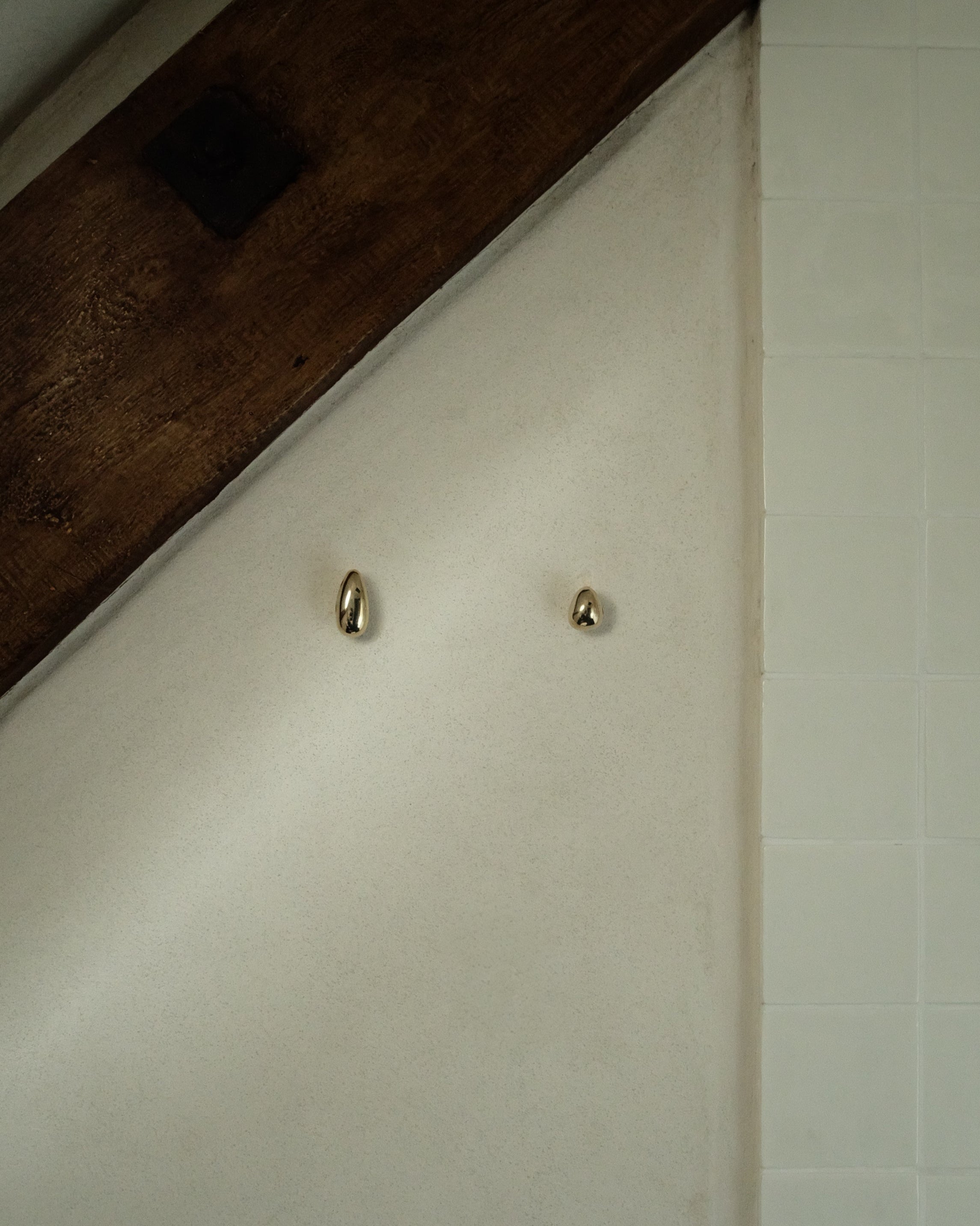 MOMI Cabinet Knob/Wall Hook Long Mini — wall-mounted brass hooks in bathroom setting