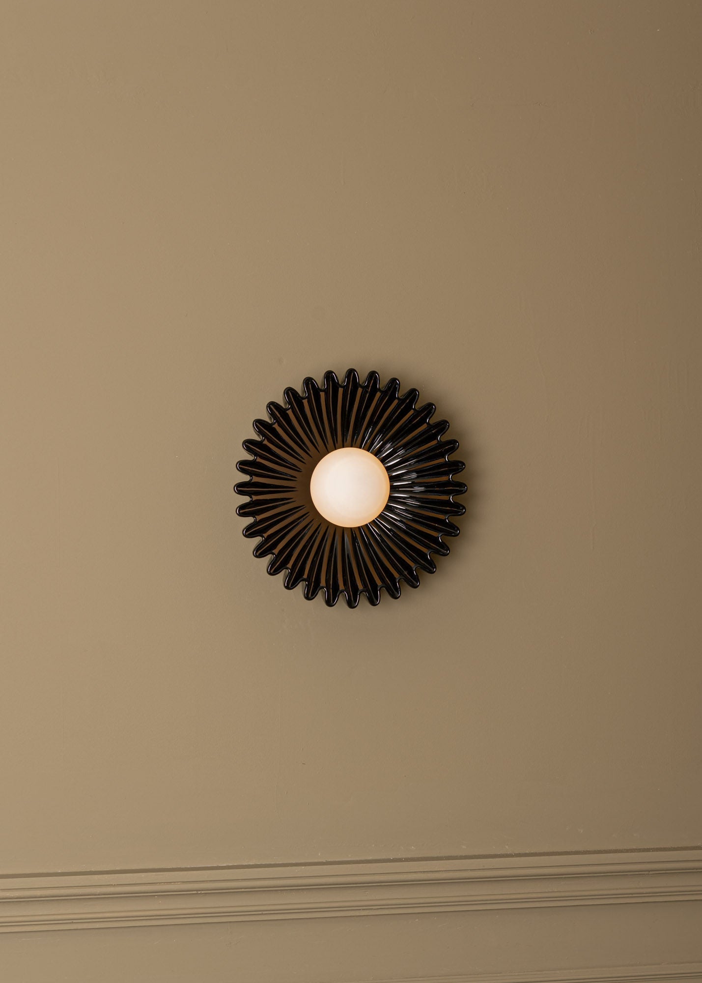 Ostro black ceramic sunburst wall light on beige wall