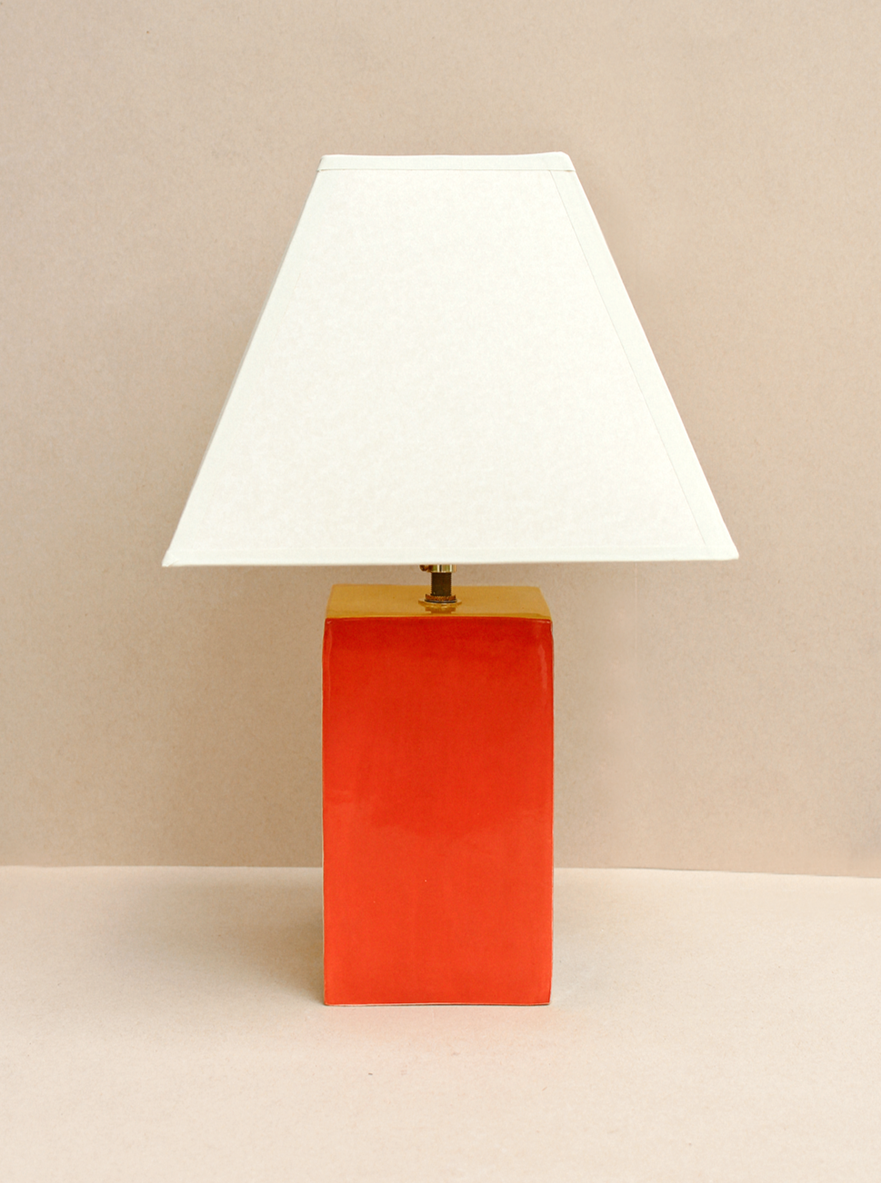The Paloma Lamp by Casa Veronica features a hand-built ceramic design with a custom square lampshade and a bold rectangular red base, set against a neutral beige background.