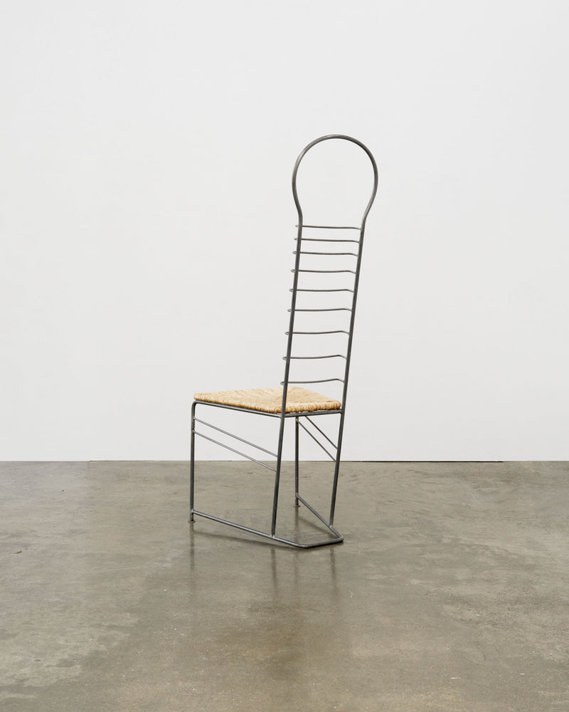 Sculptural steel chair with woven straw seat, side profile view