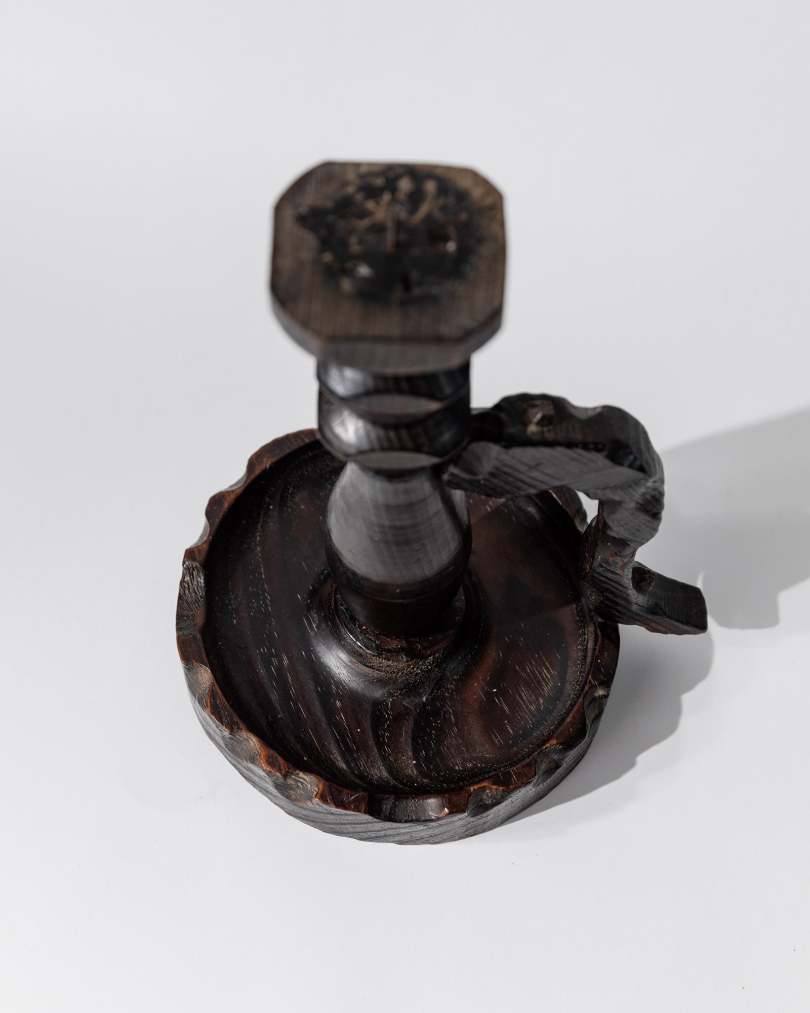 The 1960s Wooden Candleholder by Bottega Jacobs features handcarved dark wood, a carved base, and looped handle. Photographed from above on a white surface, it highlights mid-century style with its sleek silhouette.