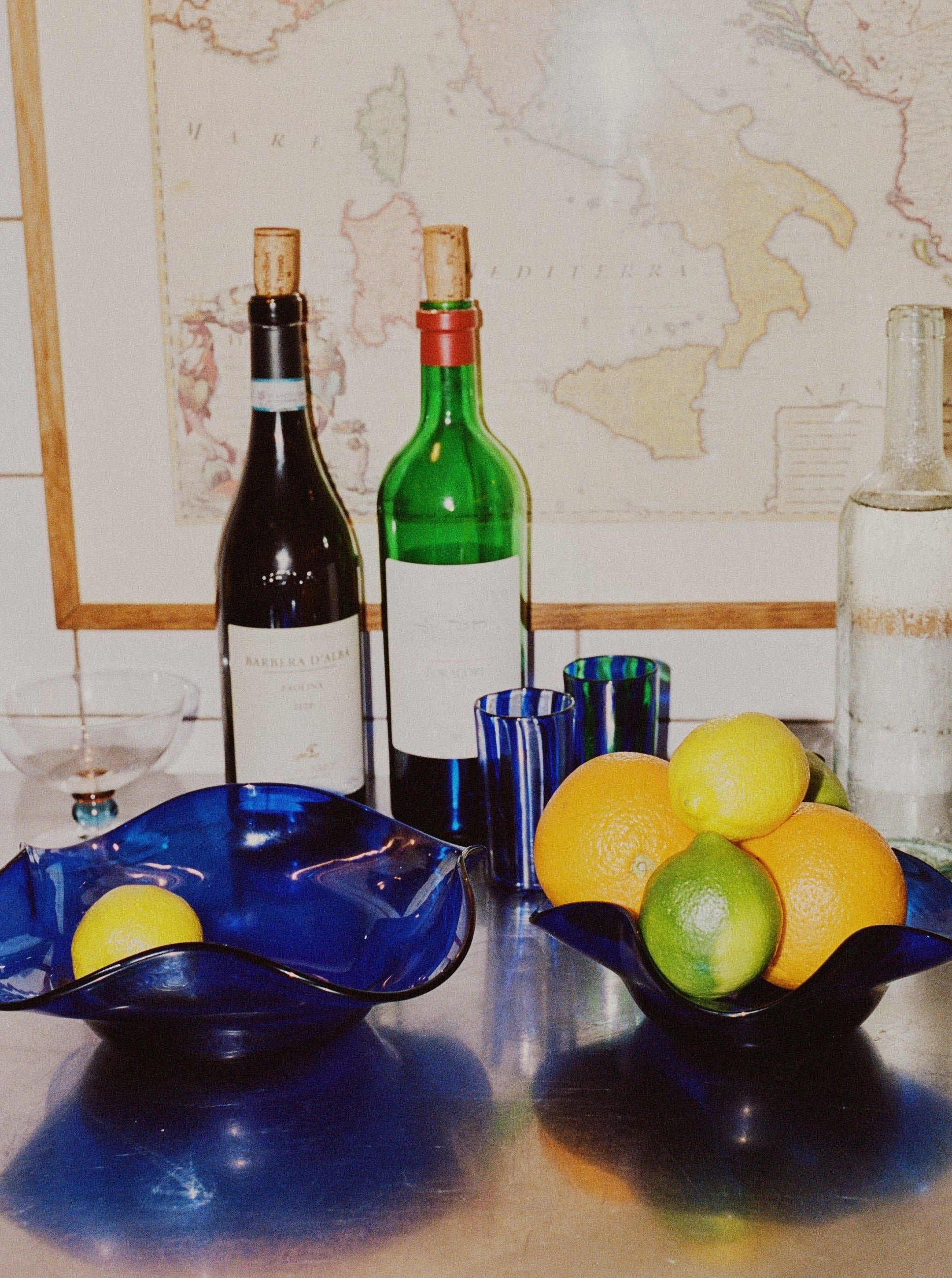 Blixen Bowl Large — side view with vibrant blue glass and citrus fruits