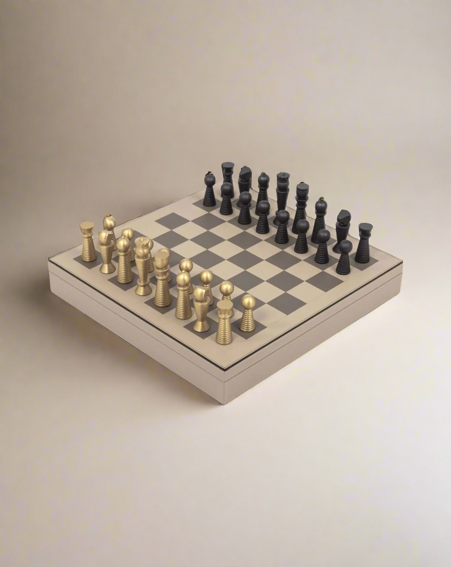 A Pinetti Chess & Checkers Game Board with a complete range of gold and black pieces, arranged and ready to start a game, is photographed from a slight angle on a white background.