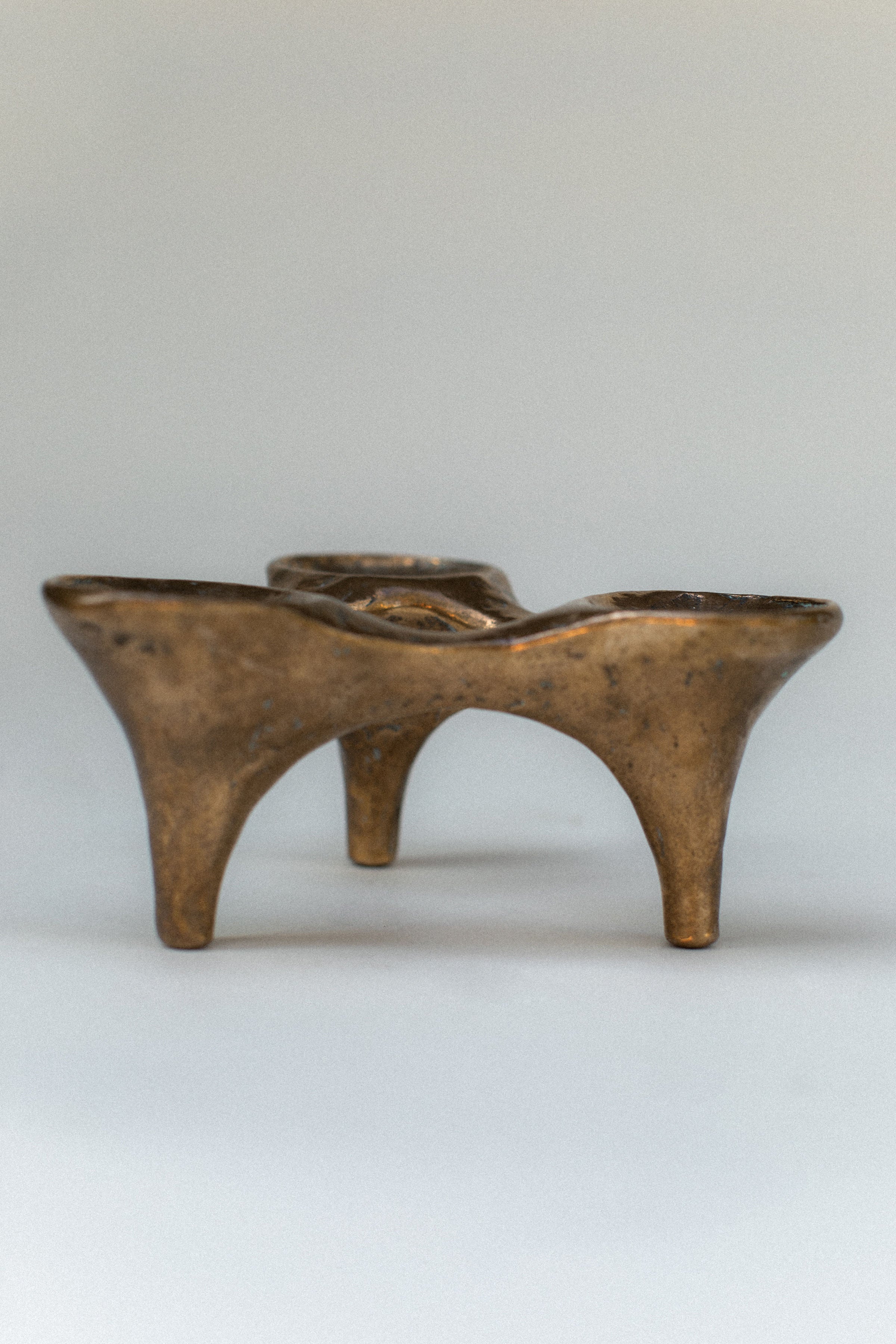 Bronze candleholder with sculptural curved legs and dual holders