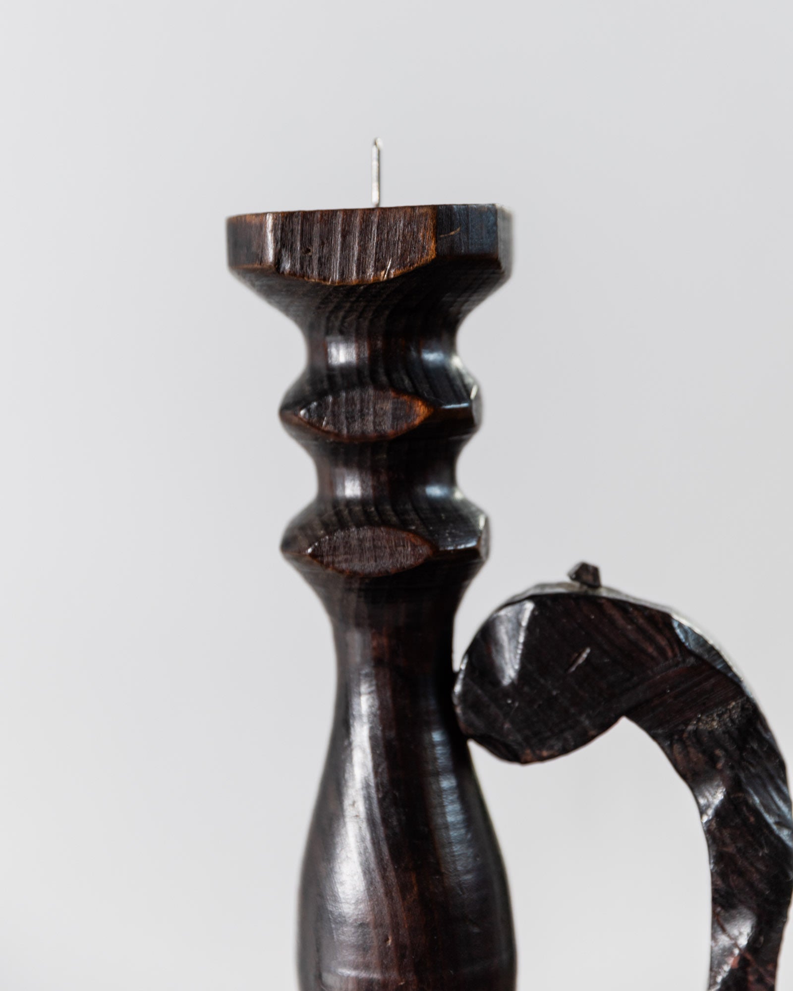 A close-up of the Bottega Jacobs 1960s Wooden Candleholder in handcarved dark wood, featuring a textured Brutalist design and visible metal spike on top against a plain, light background.