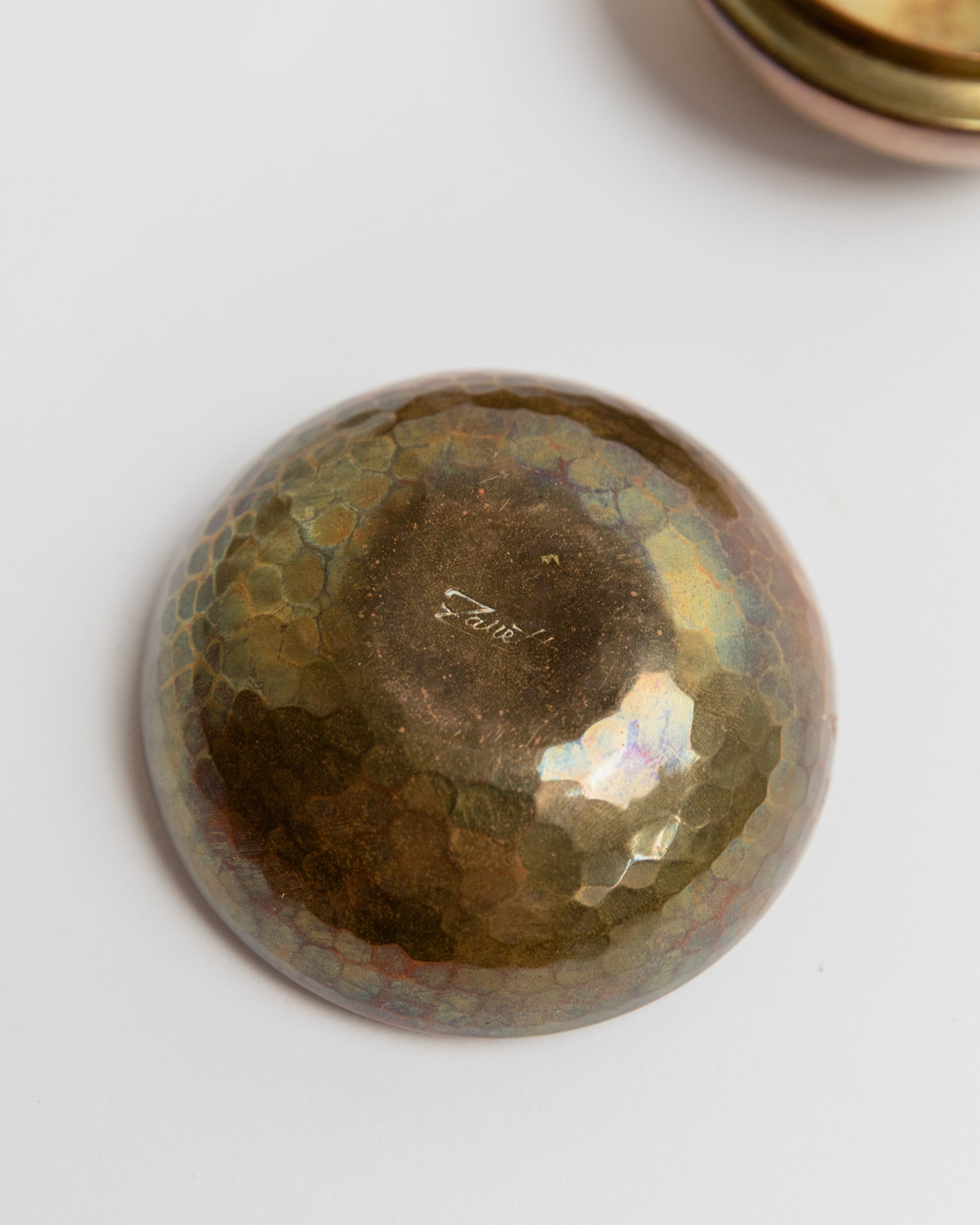 Interior view of vintage brass tin showing iridescent patina and craftsmanship