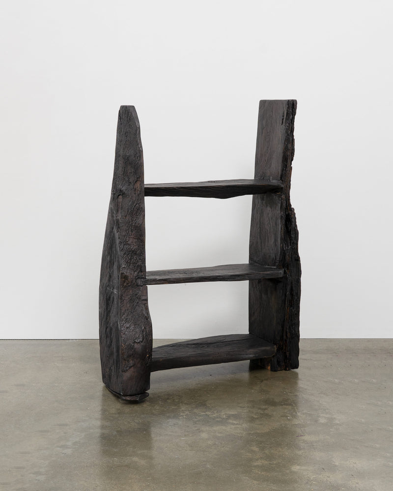 Dark charred wood brutalist bookcase with three shelves and raw edges