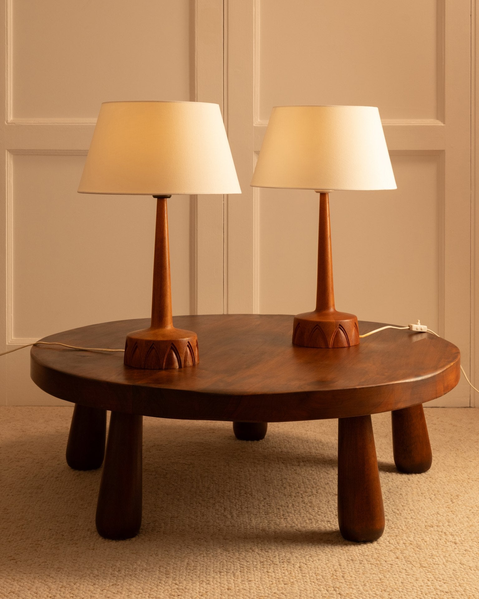 Two Swedish wooden table lamps with cream shades on round coffee table