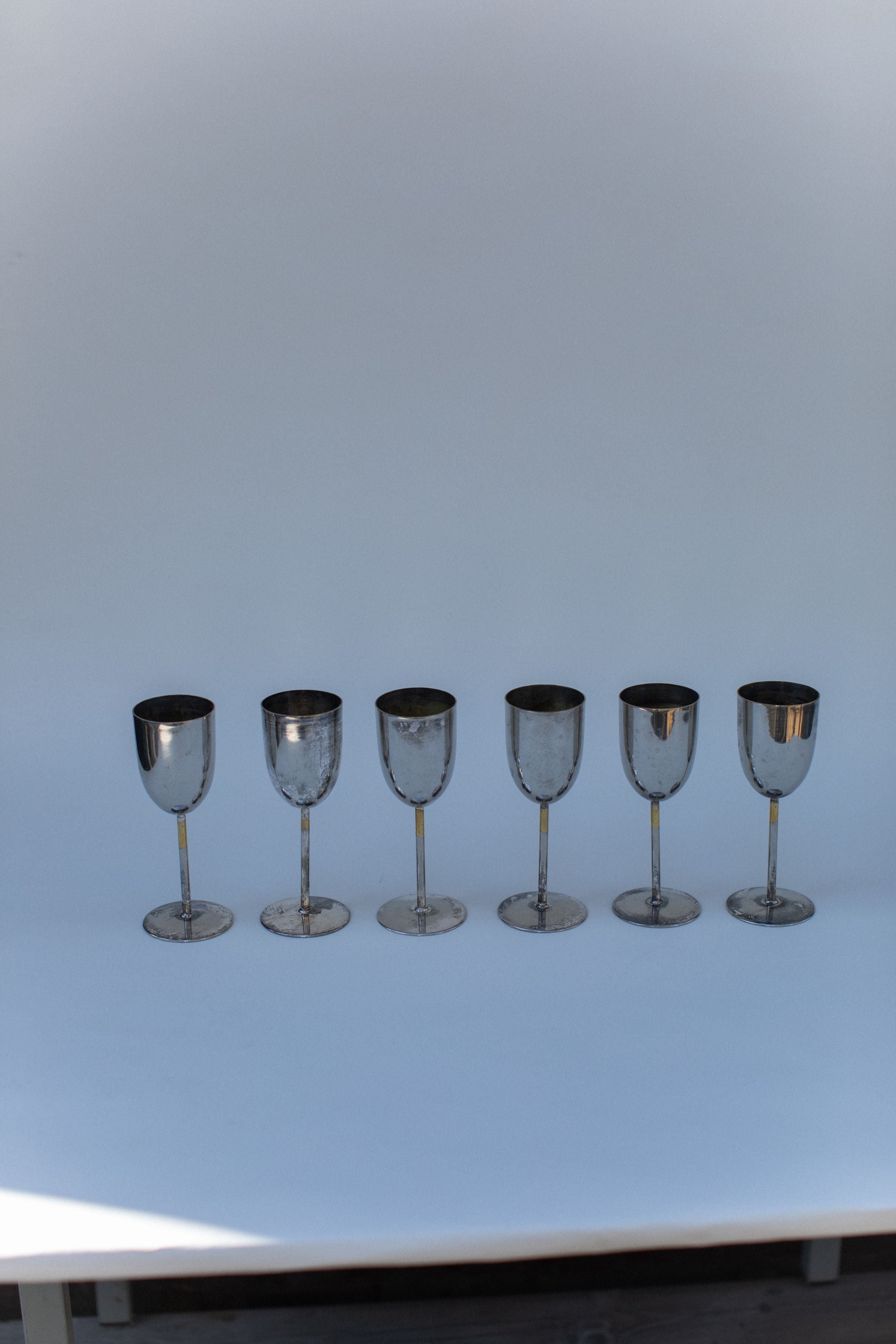 Set of six brass champagne glasses with stems on white surface