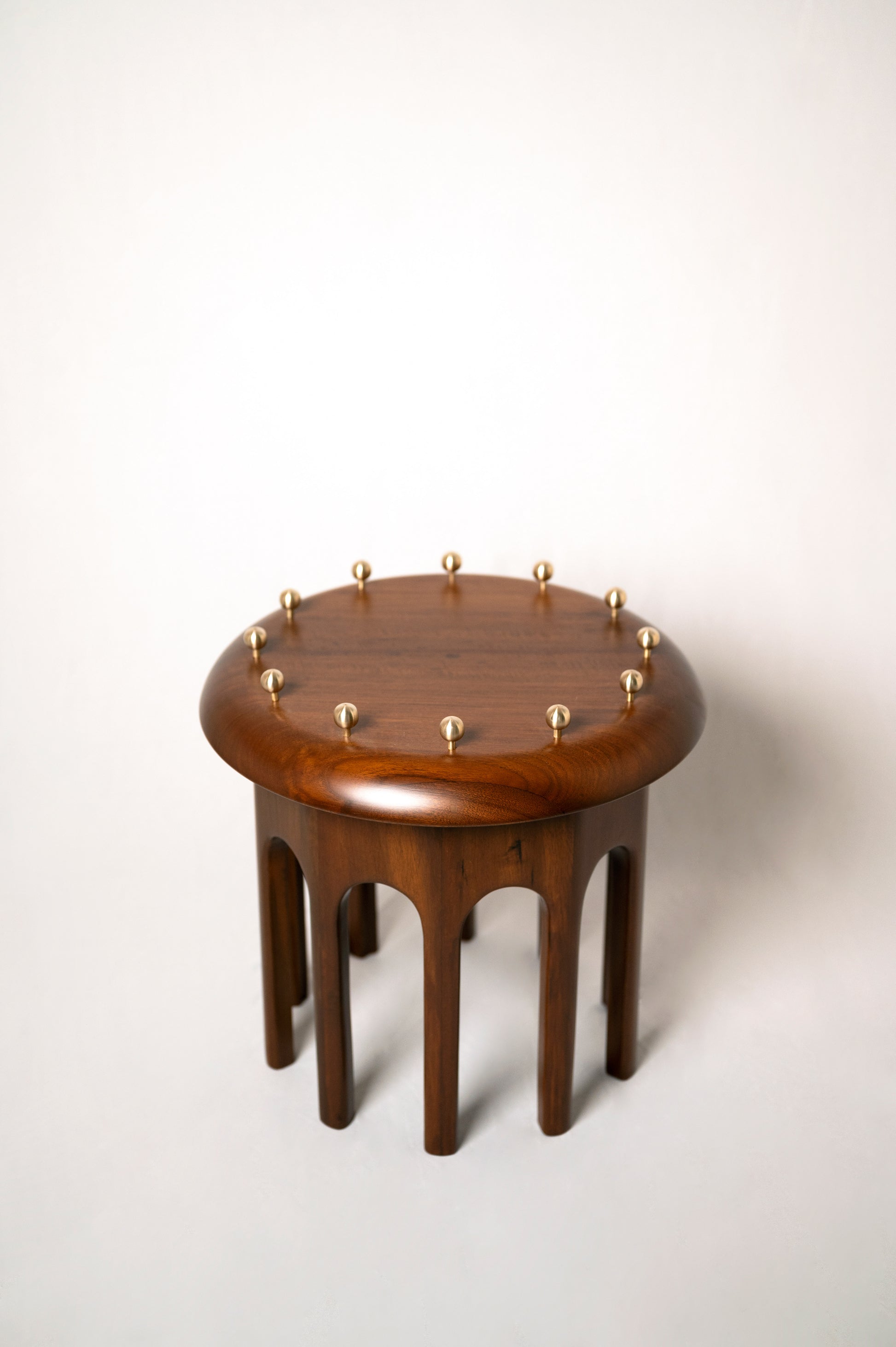 Corona Side Table — top view of round wooden surface with brass accents
