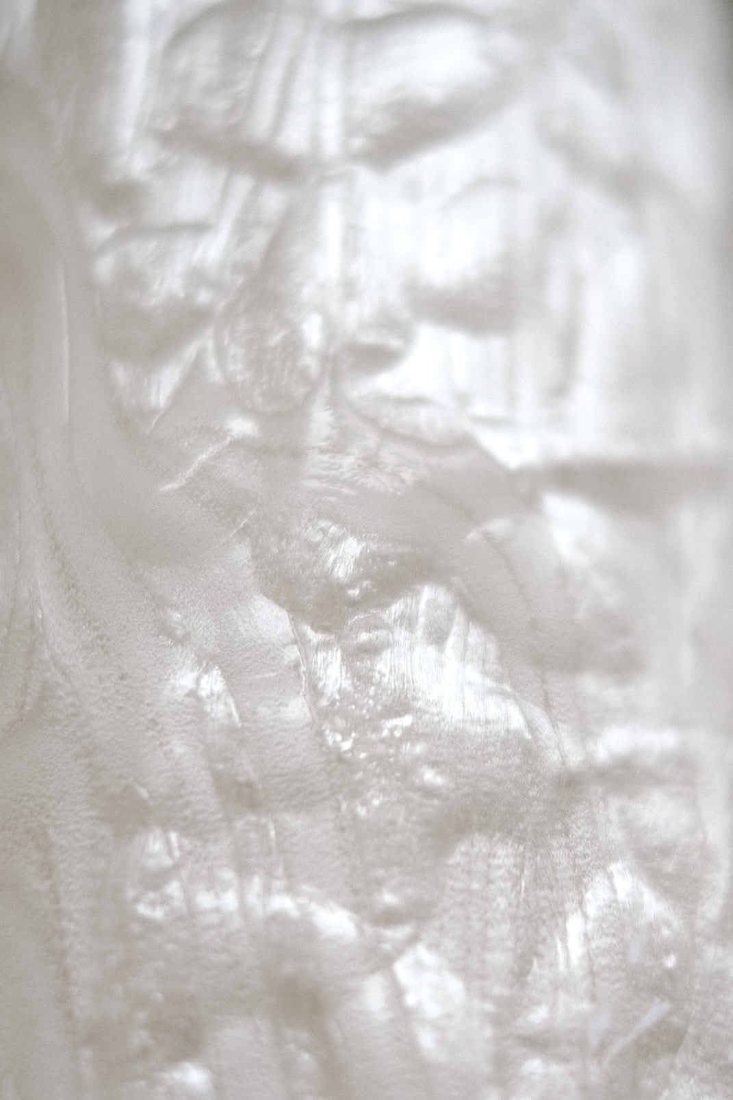 Close-up of the Set of 2 Mother-of-pearl Wall Lamps from septembre studios, featuring a white, semi-translucent crinkled texture with subtle light reflections, evoking vintage and 1980s-inspired design.
